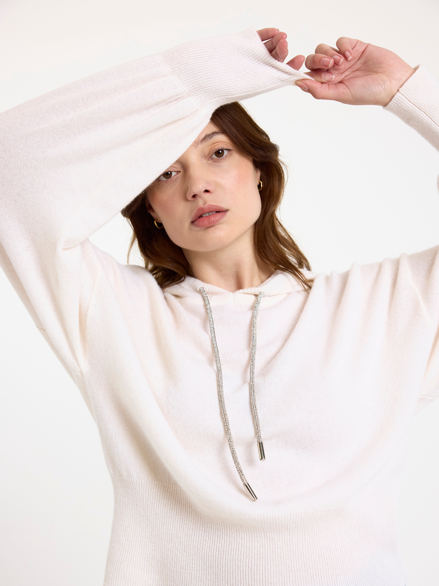 Woman wearing a white hoodie with a plain background