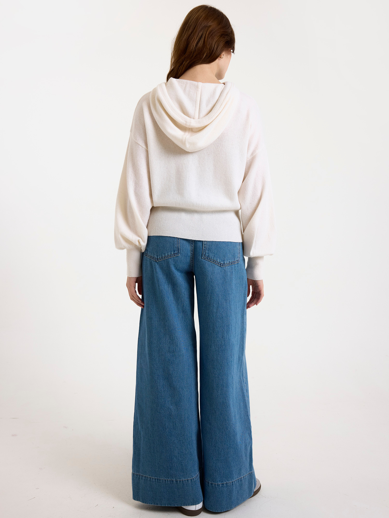 Woman wearing a white hoodie and blue jeans on a white background