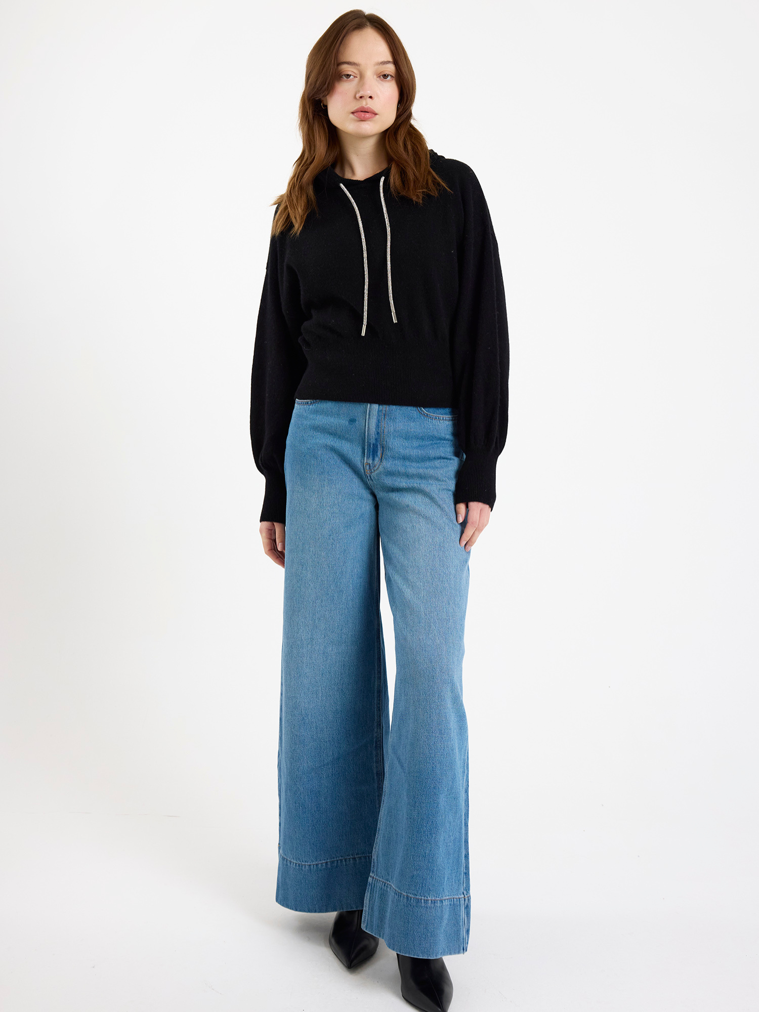 Woman wearing a black hoodie and blue jeans on a white background