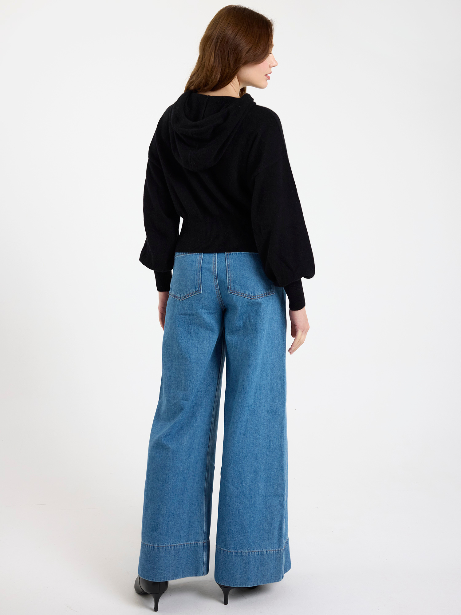 Woman wearing a black top and blue jeans on a white background