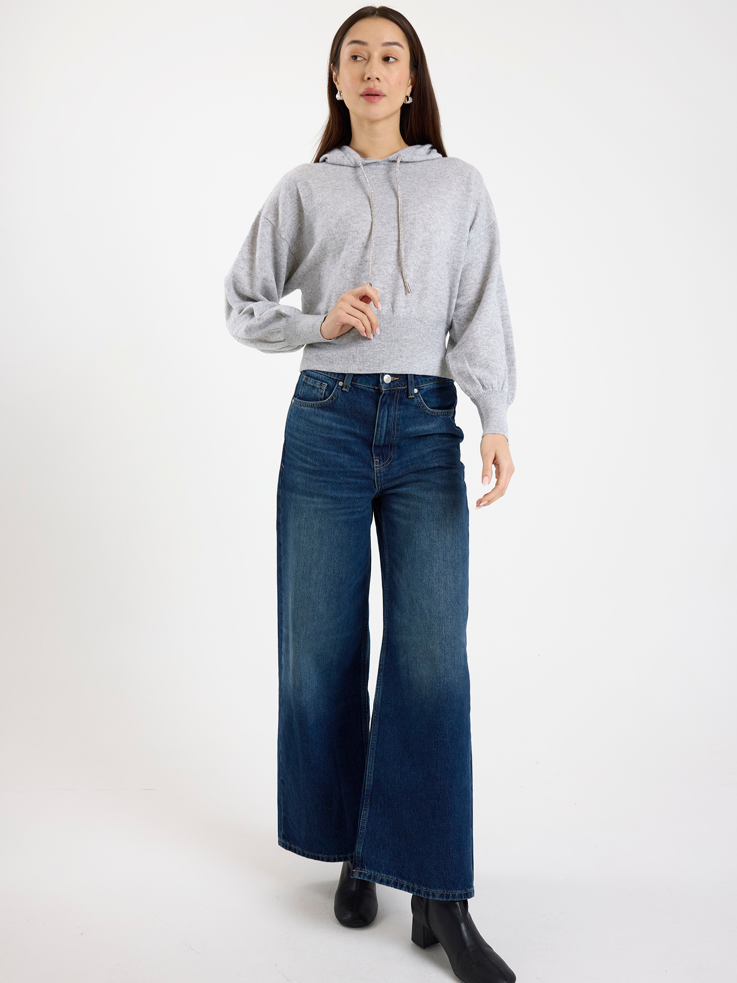 Woman wearing a grey hoodie and blue jeans on a white background