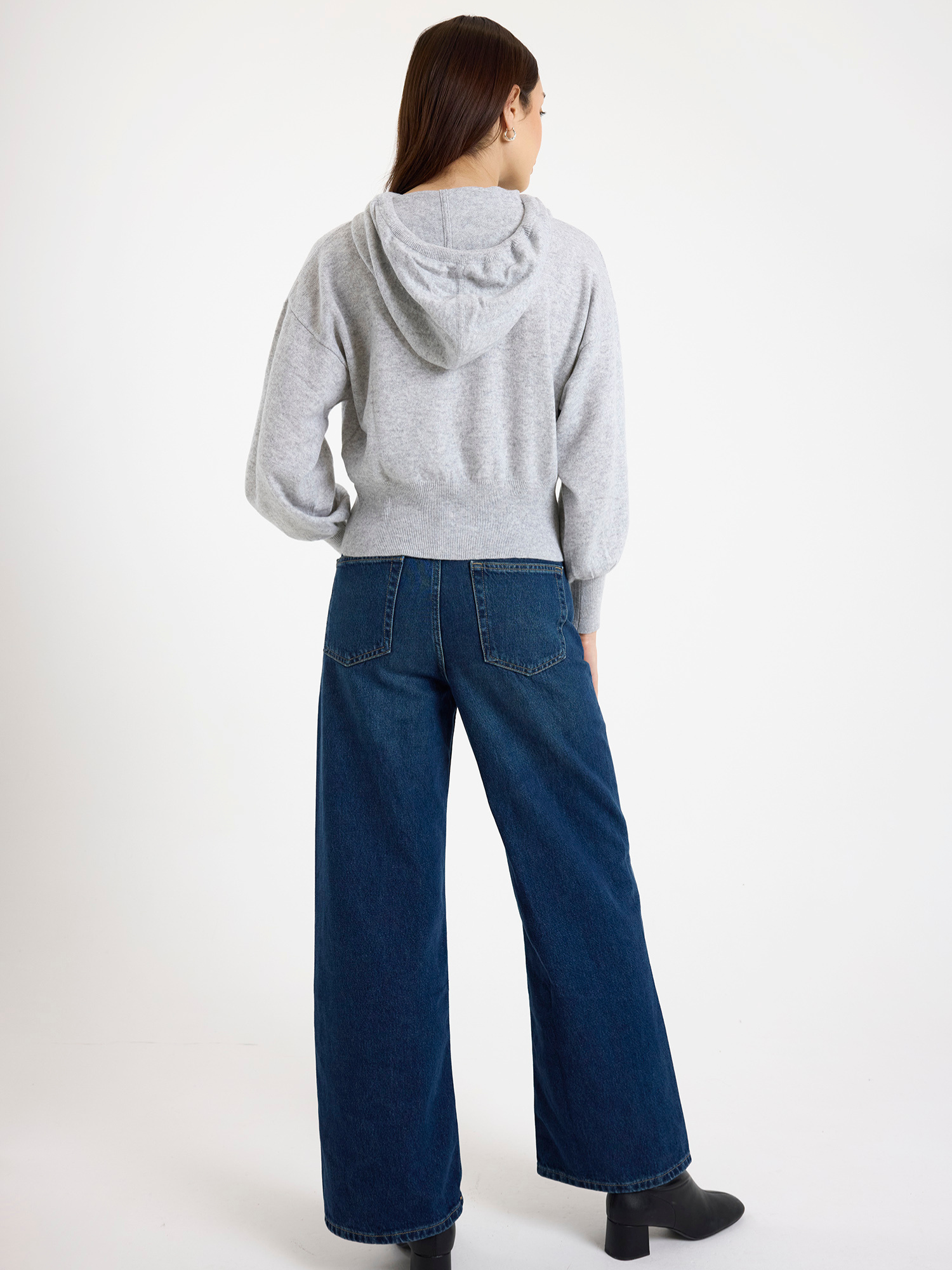 Woman wearing a grey hoodie and blue jeans on a white background