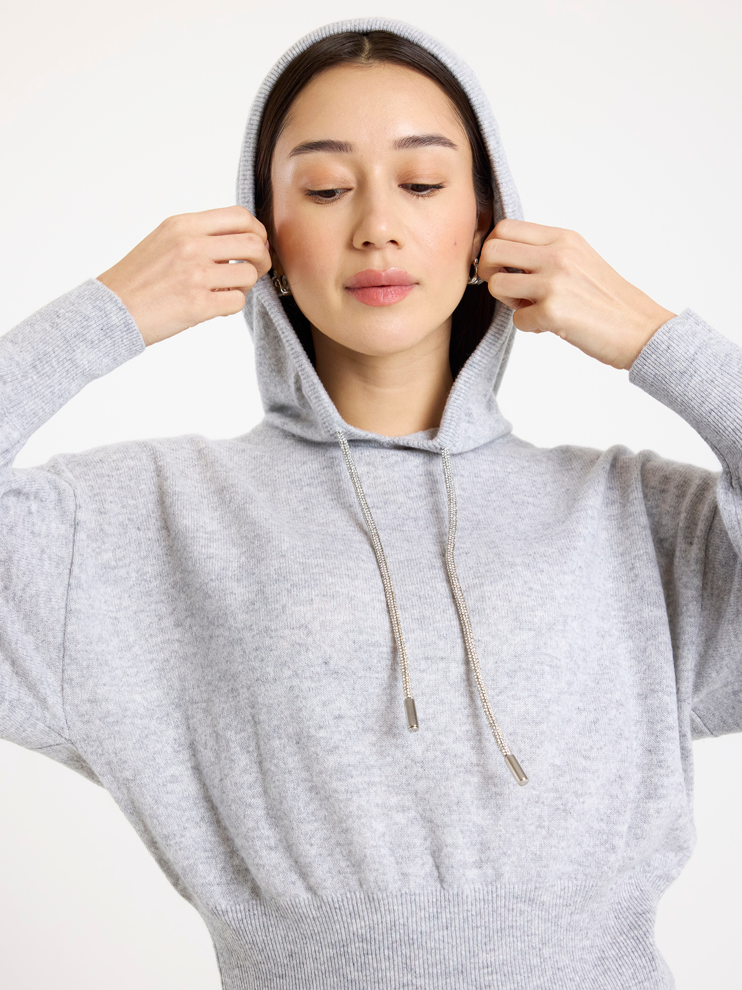 Woman wearing a grey hoodie against a white background