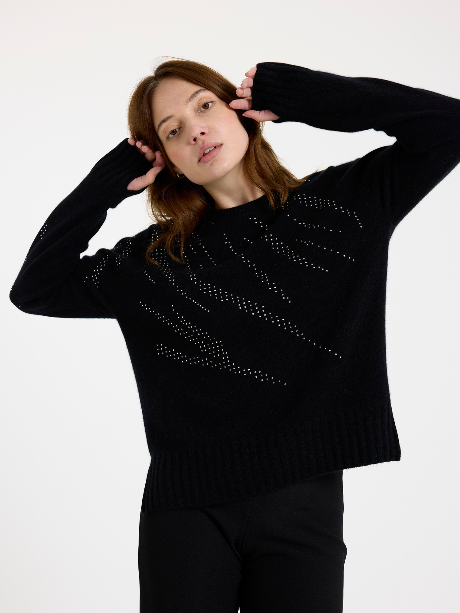 Woman wearing a black sweater with silver stud zebra pattern on a white background