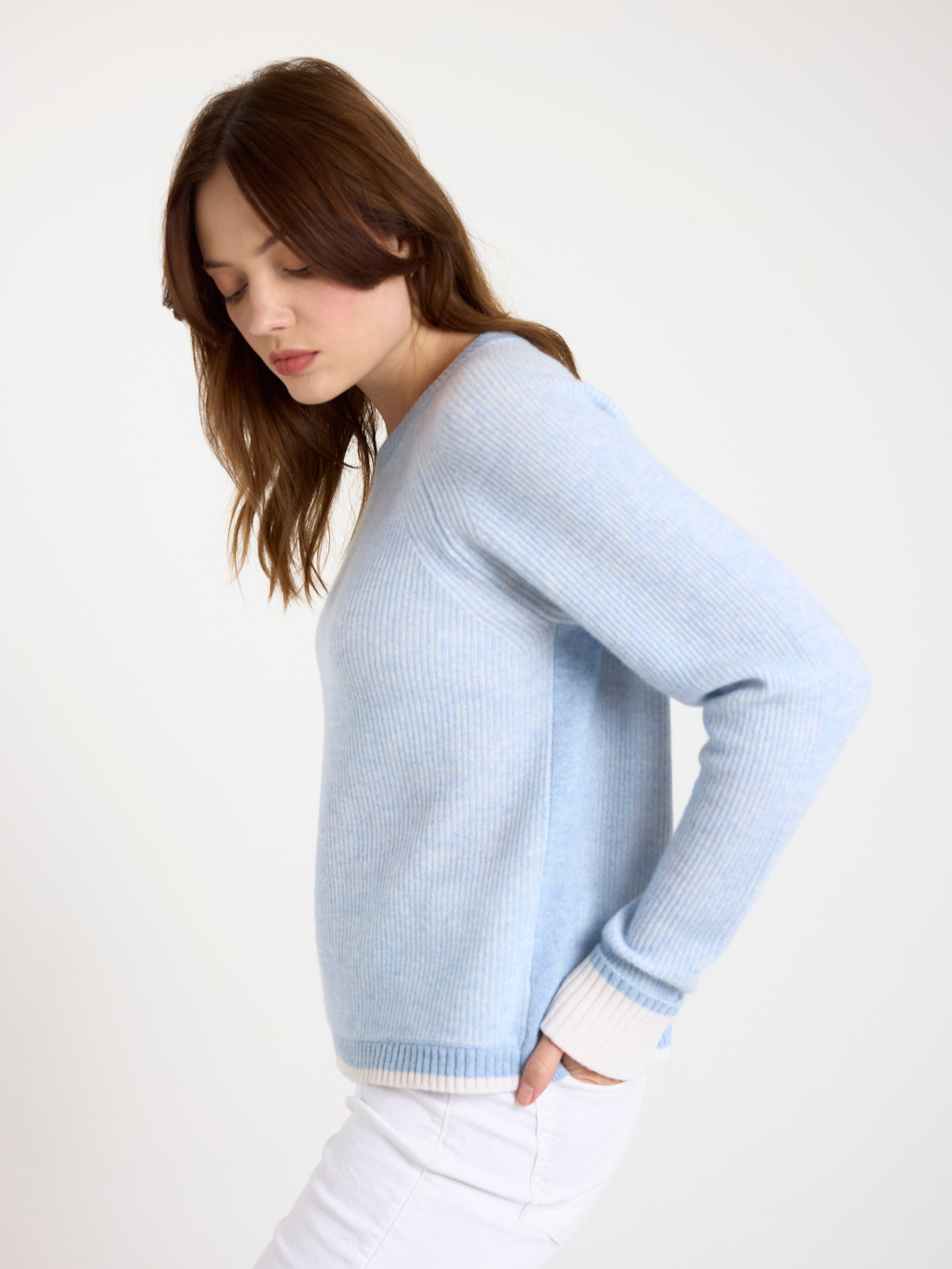 Woman wearing a ribbed light blue sweater against a white background
