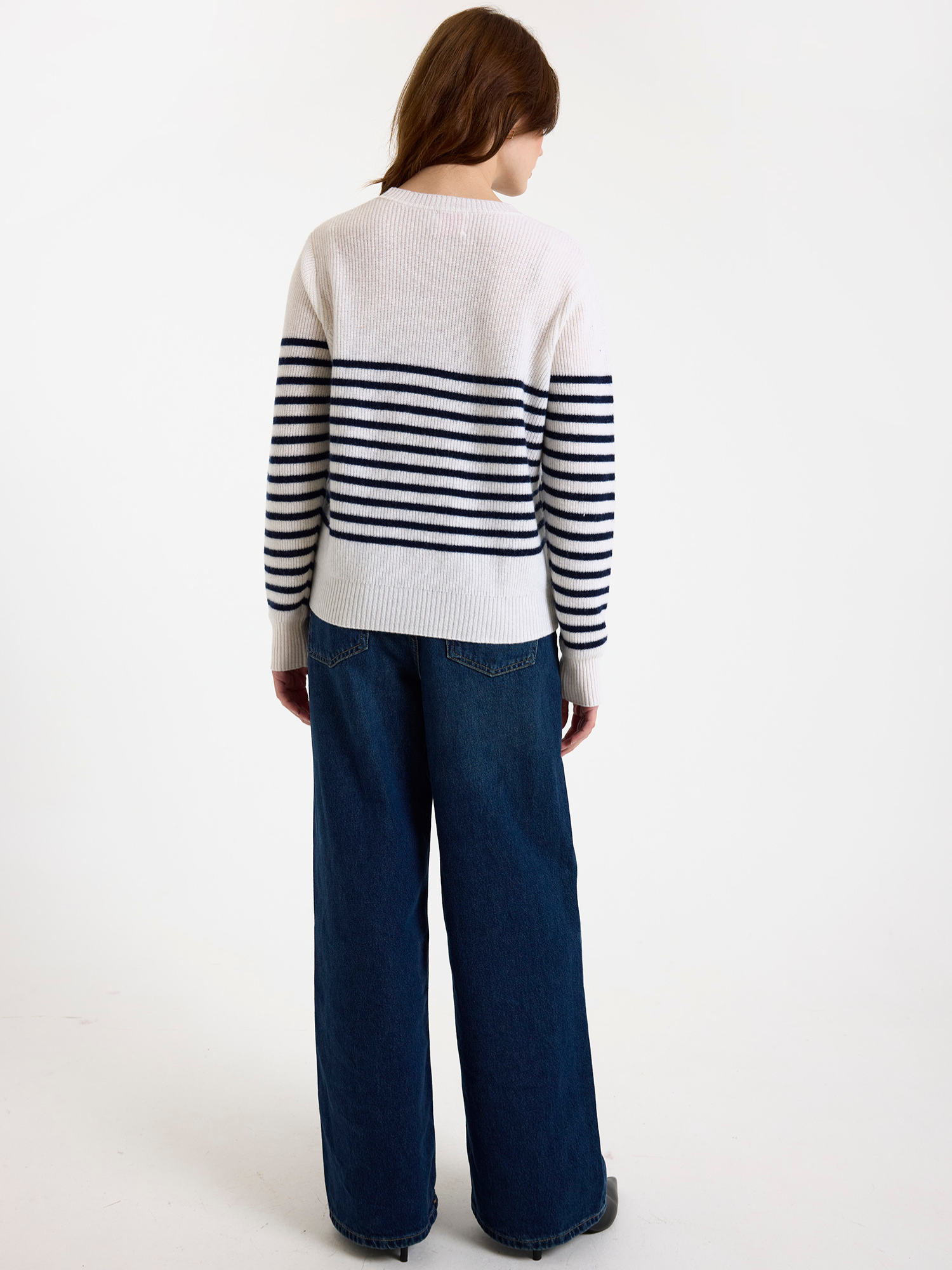 Woman wearing a striped sweater and blue jeans on a white background