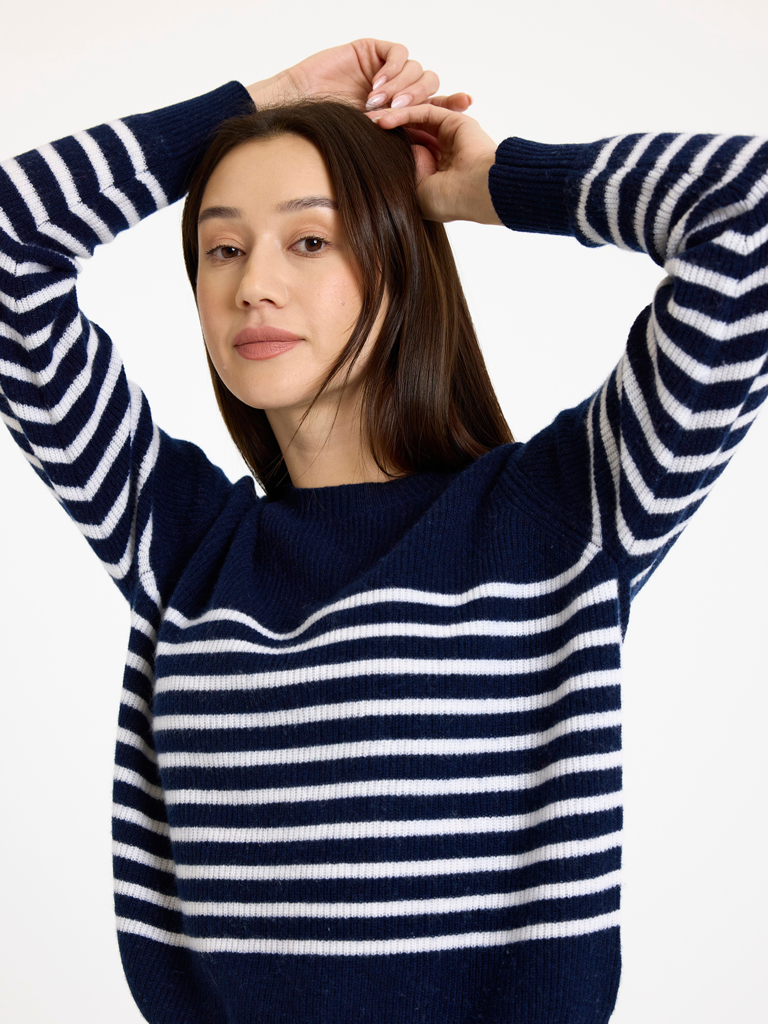 Woman wearing a navy and white striped sweater against a plain background