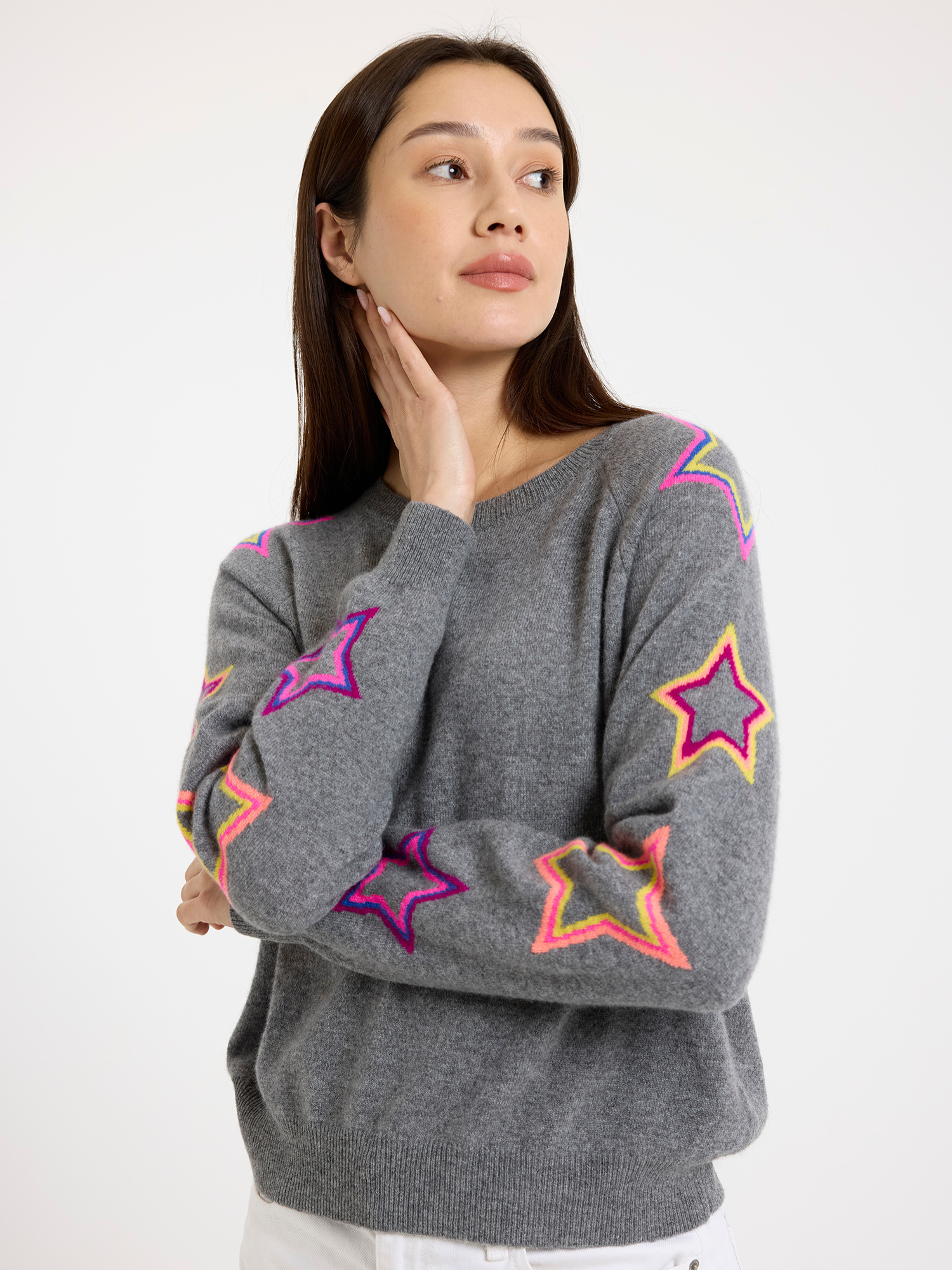 Woman wearing a grey sweater with colourful star patterns on a white background