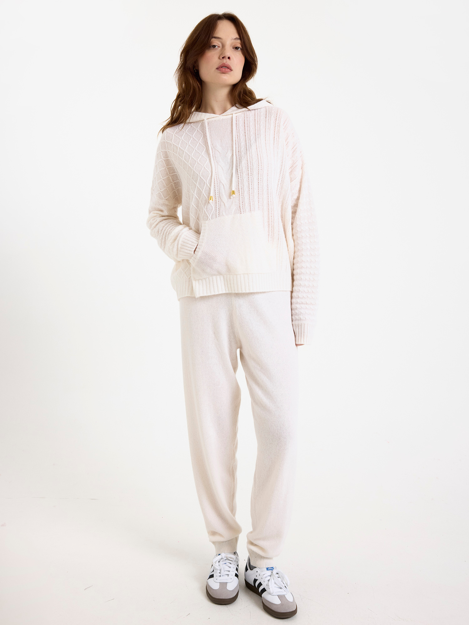 Women wearing a white cable knit jogger set with a matching hoodie and joggers on a white background
