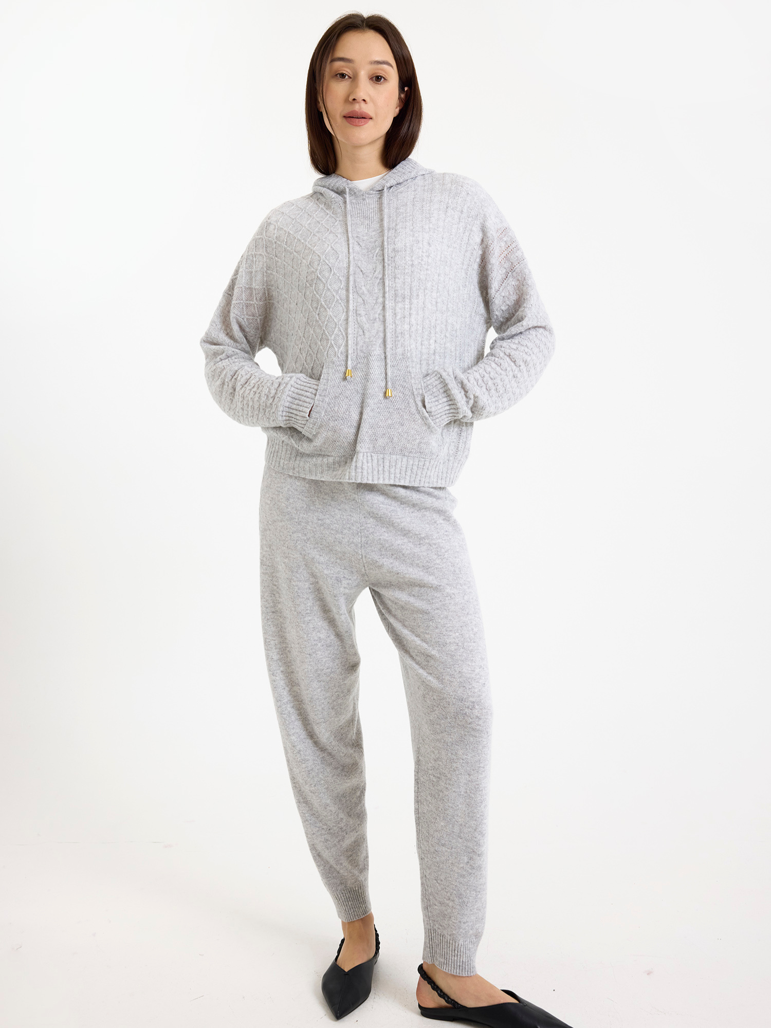Woman wearing a grey hoodie and joggers set on a white background