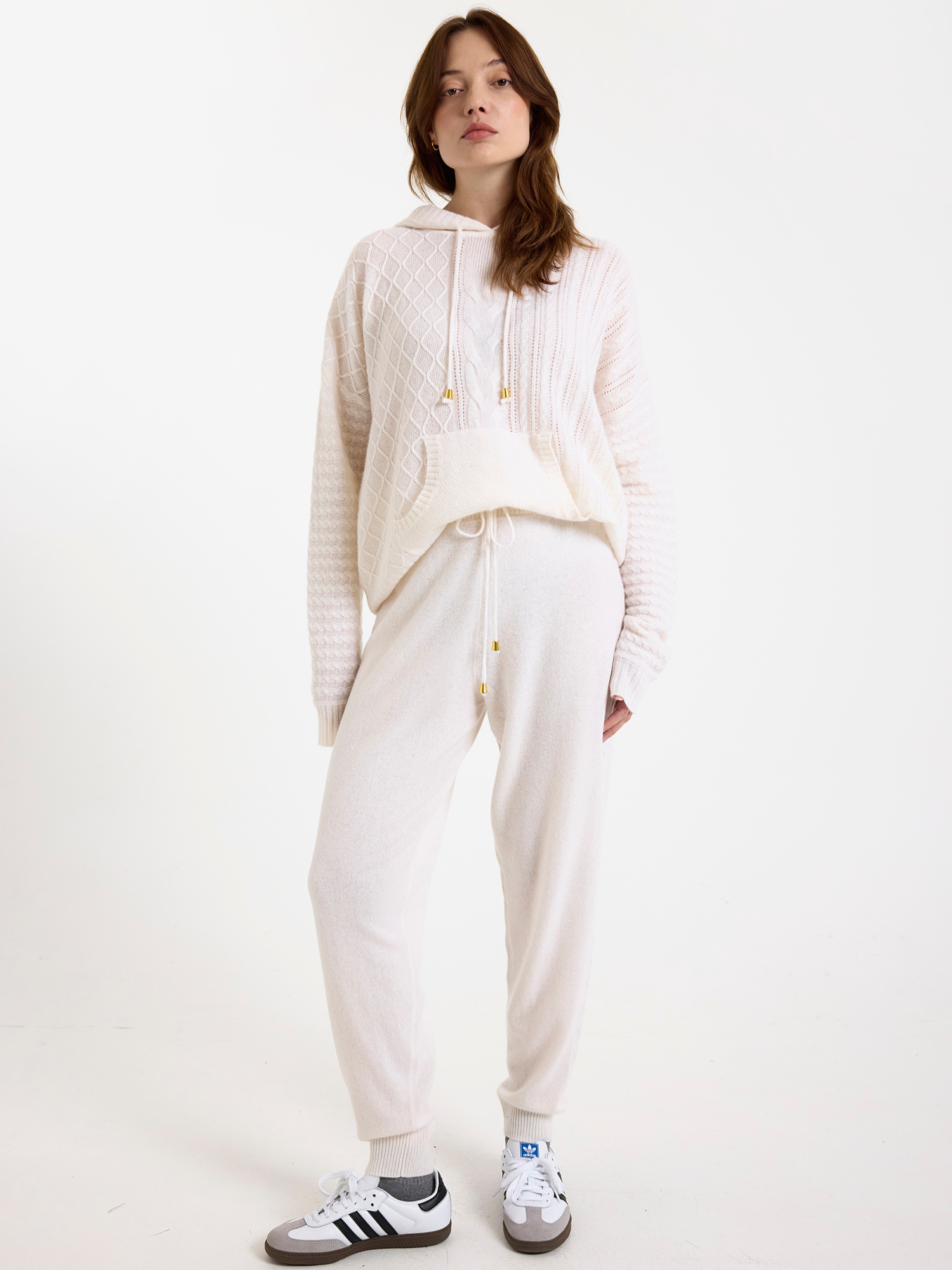Women wearing a white cable knit jogger set with a matching hoodie and joggers on a white background