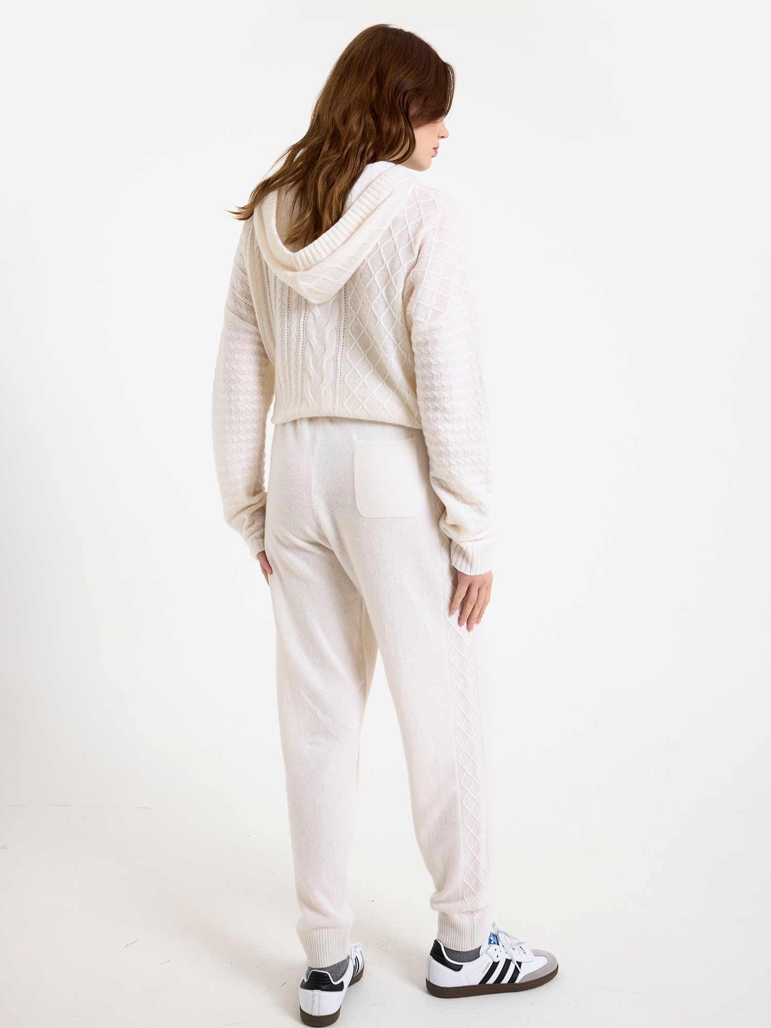 Women wearing a white cable knit jogger set with a matching hoodie and joggers on a white background