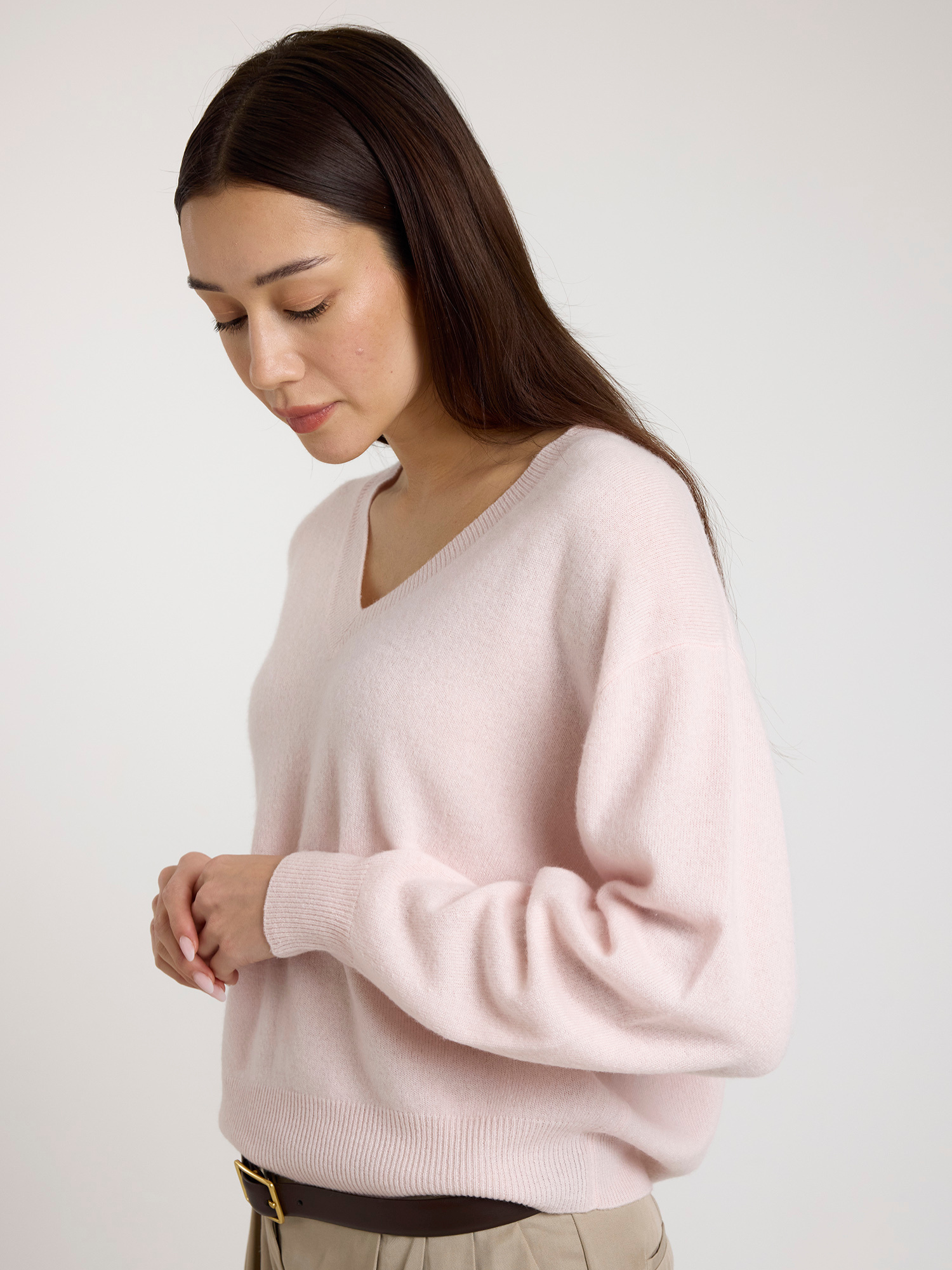 Woman wearing a light pink sweater against a plain background