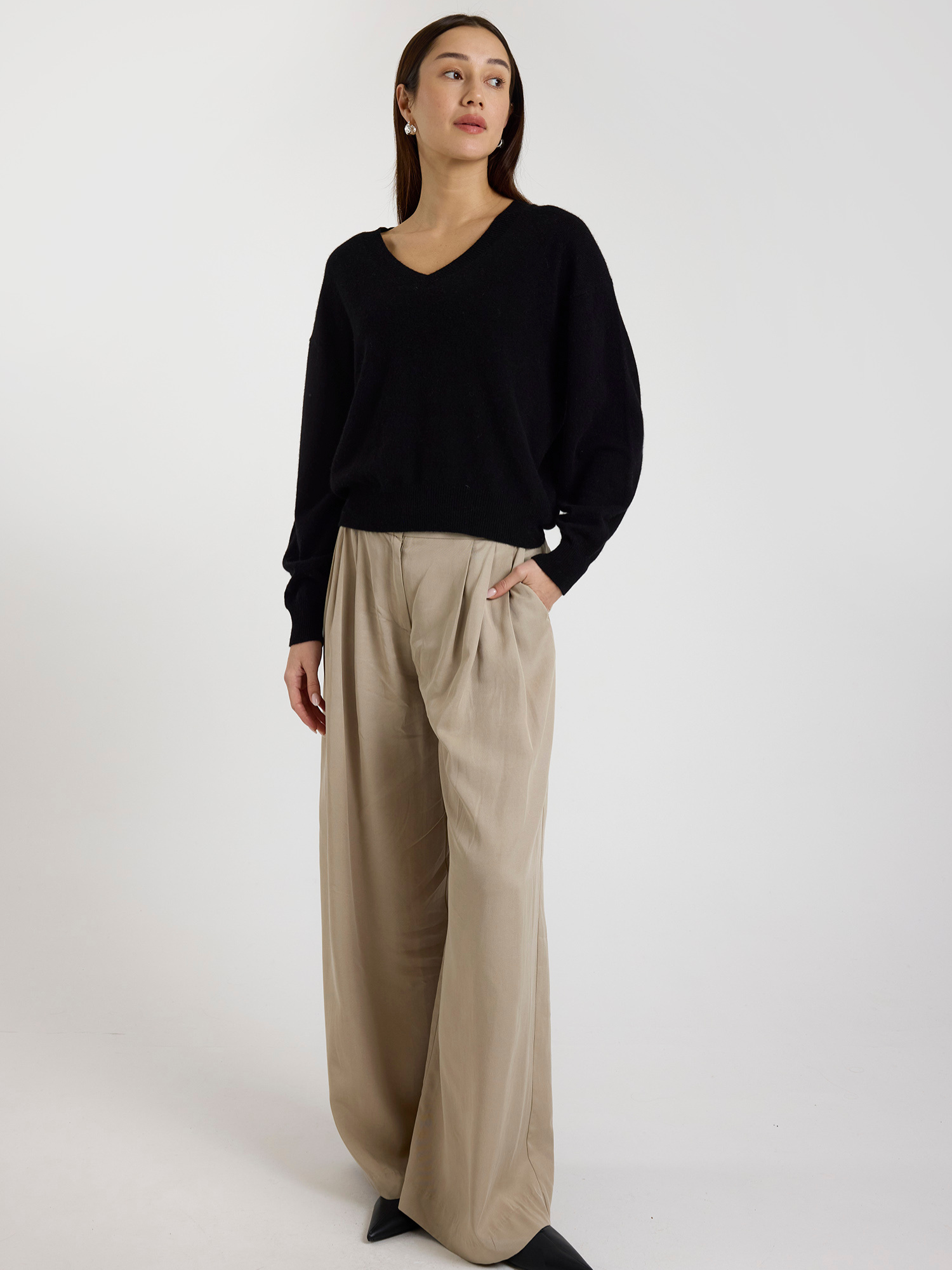 Woman wearing a black sweater and beige pants on a white background