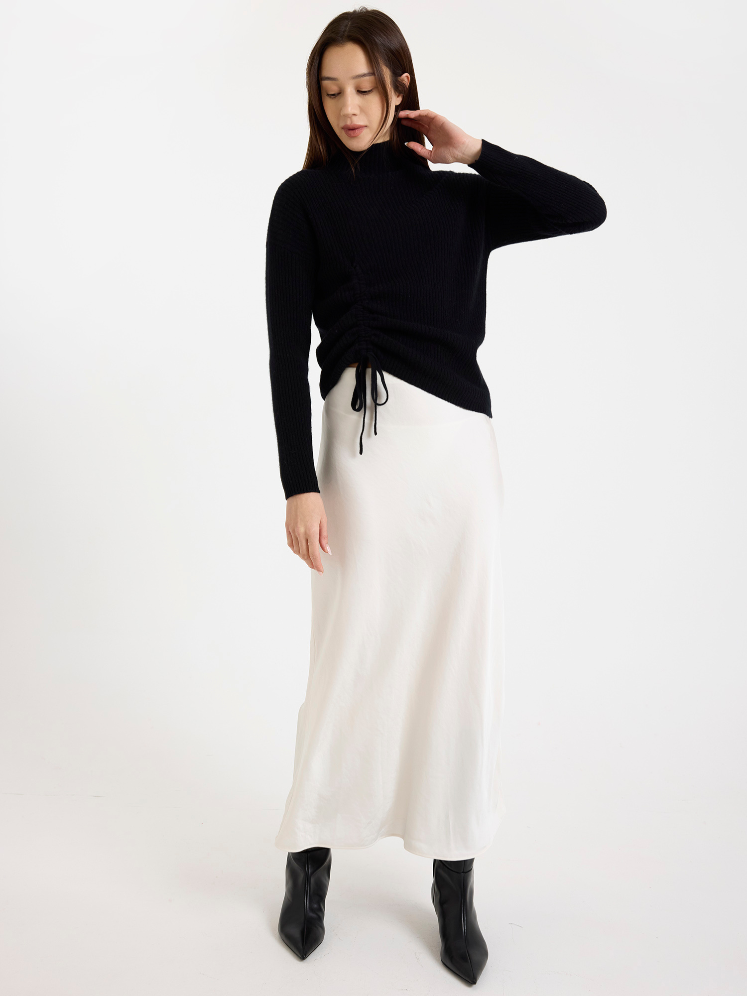 Woman wearing a black sweater and white skirt on a white background