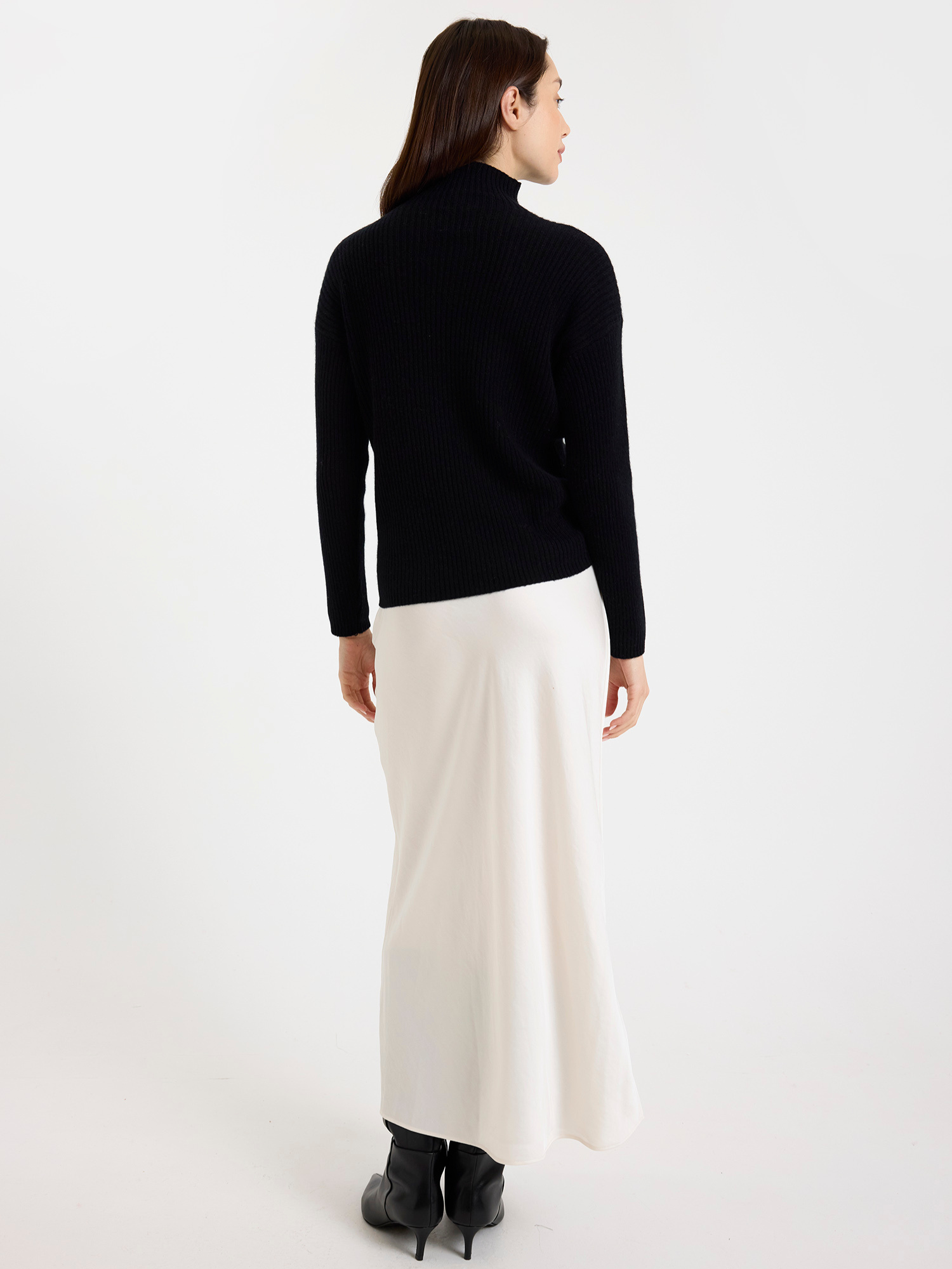 Woman wearing a black turtleneck and white skirt on a white background