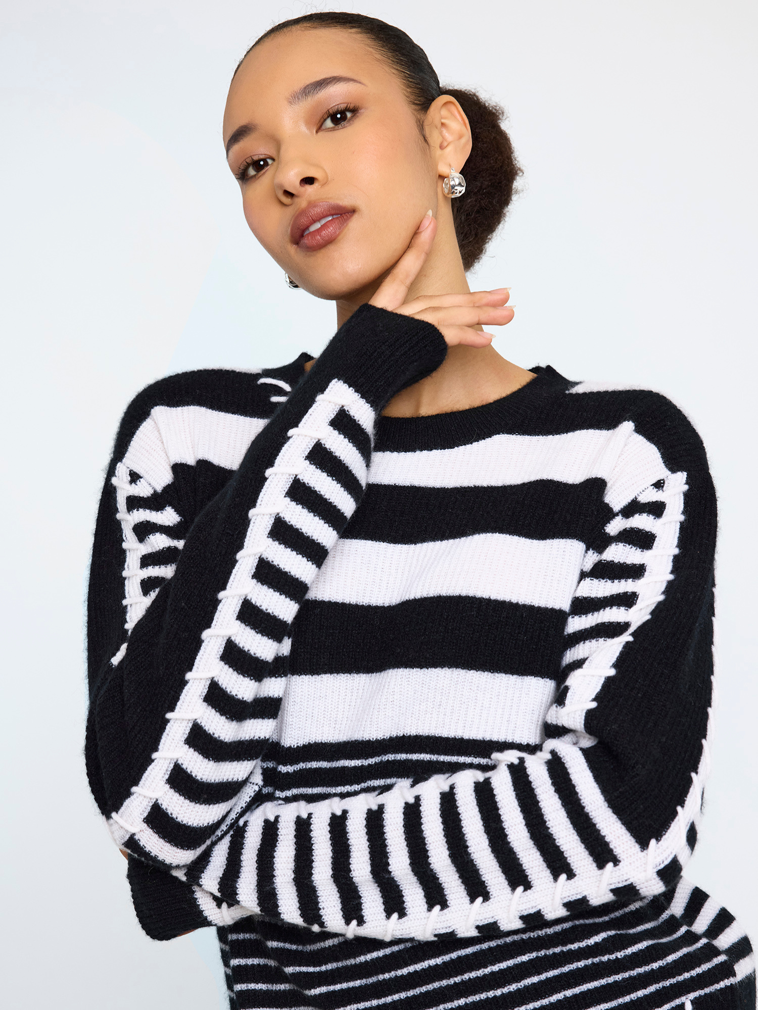 Woman wearing a black and white striped sweater against a plain background