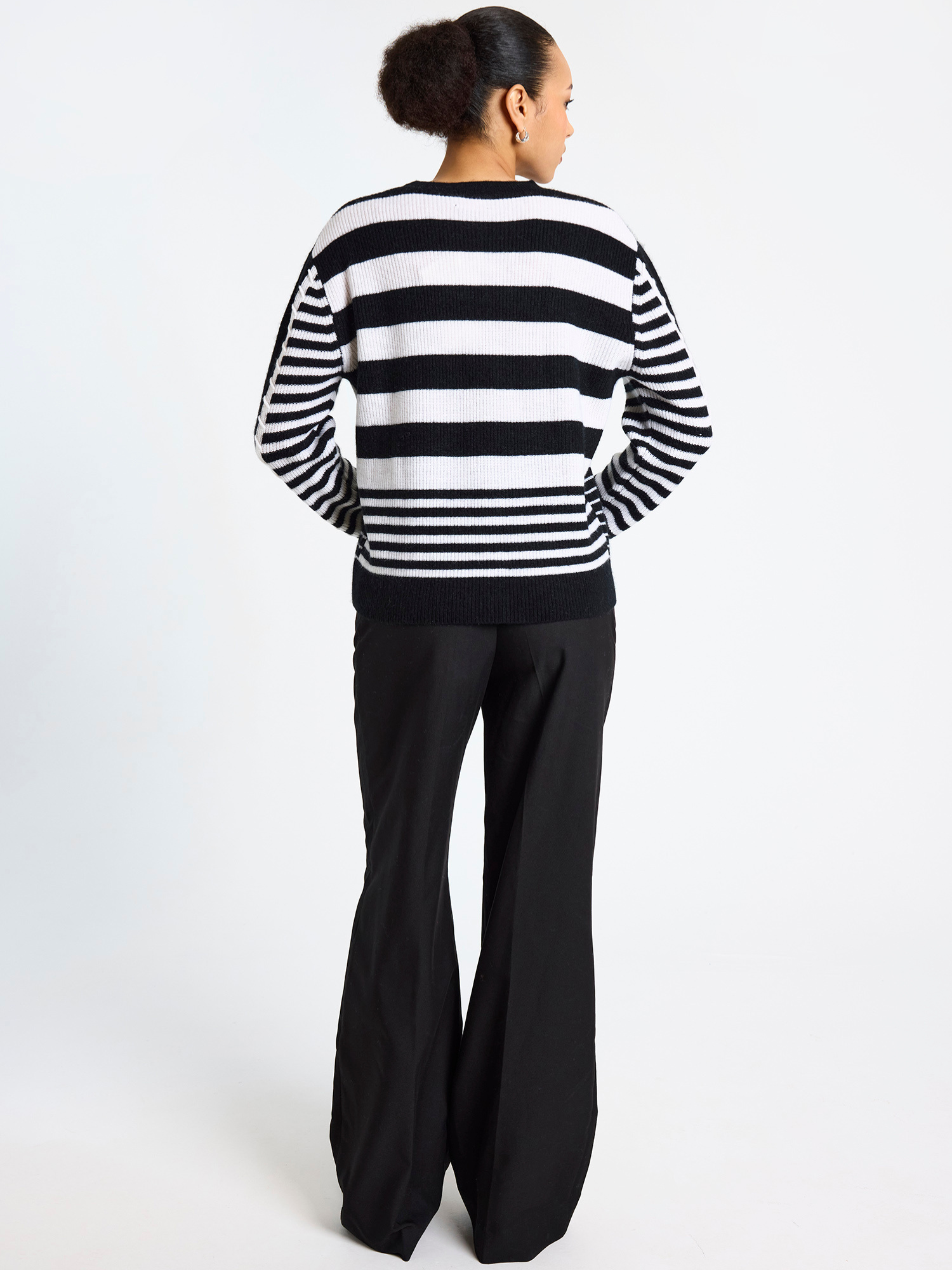 Woman wearing a black and white striped sweater with wide-leg pants on a white background