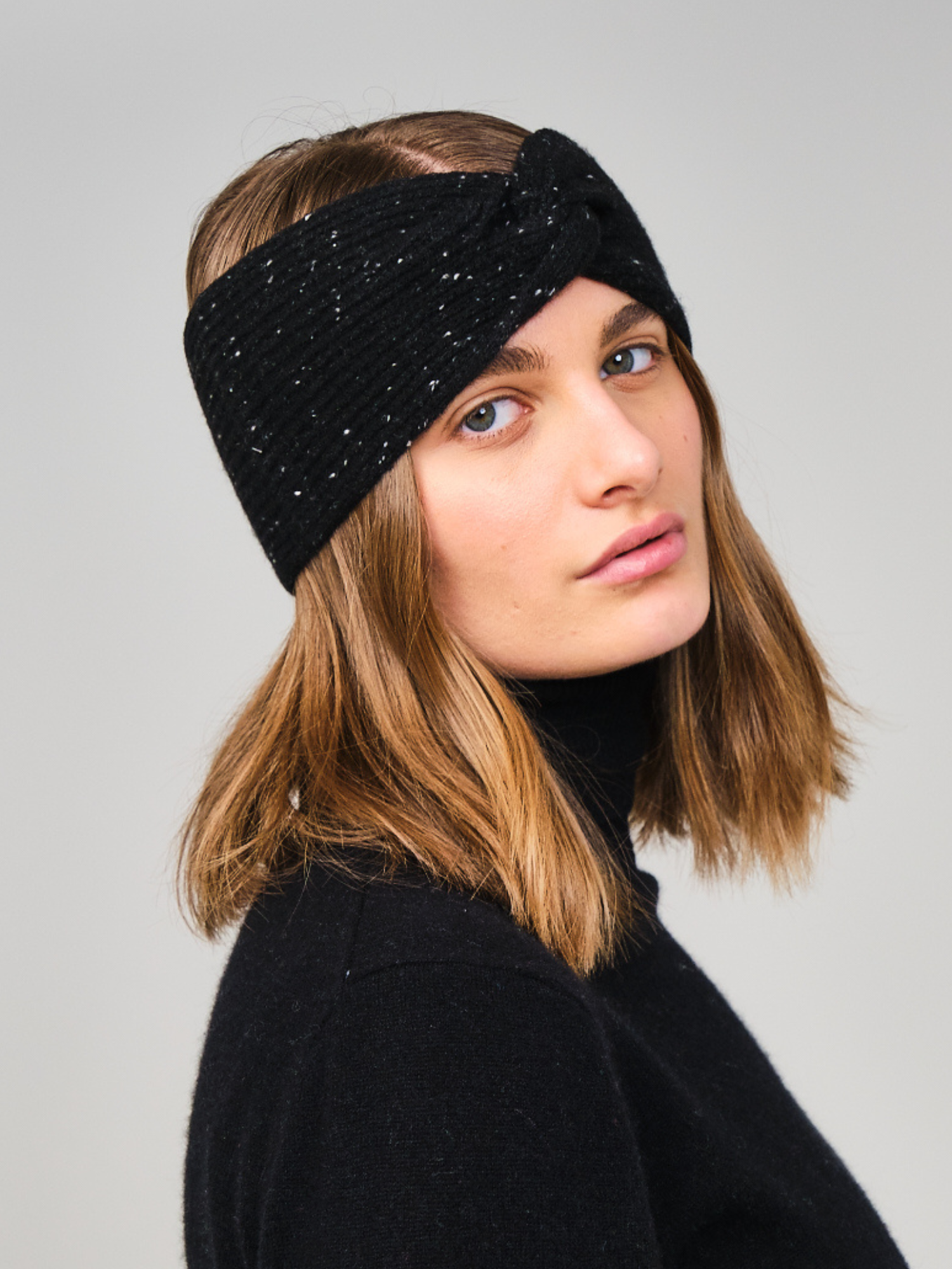 Woman wearing a black textured headband against a gray background