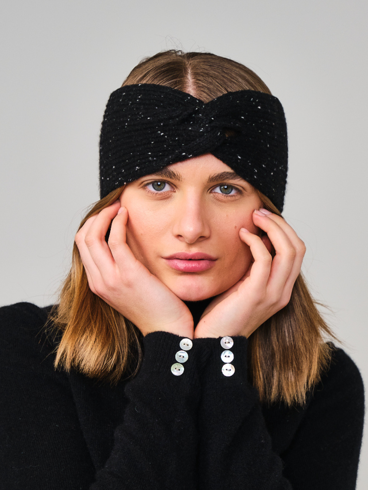 Woman wearing a black headband with a textured pattern against a plain background