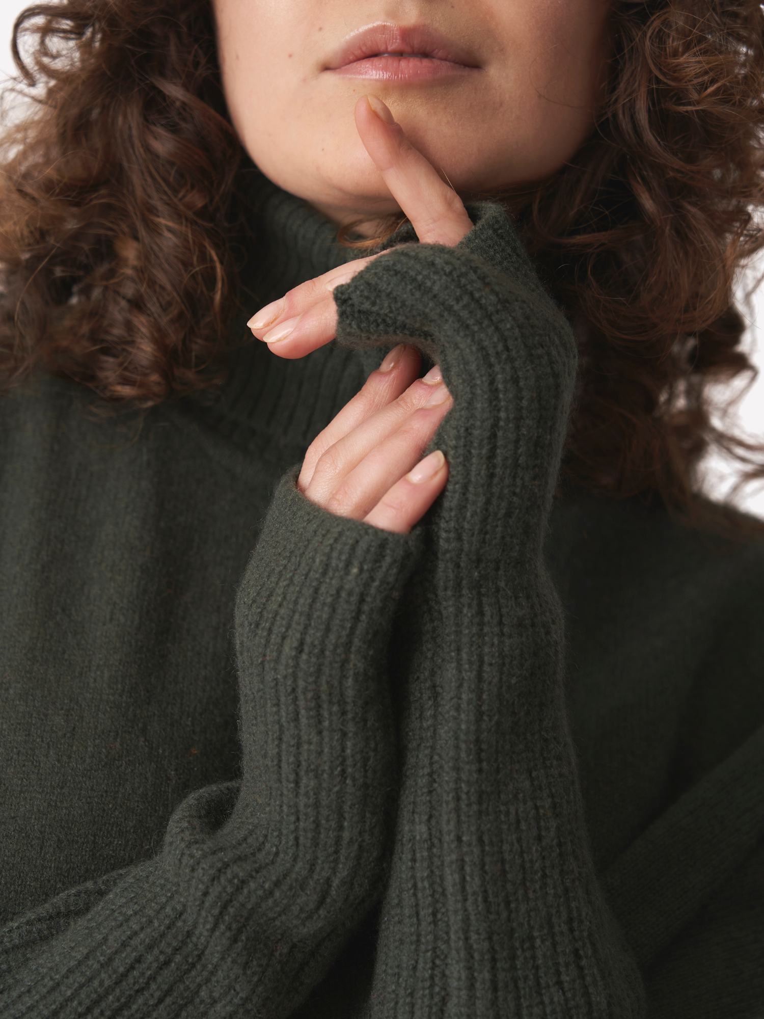 Person wearing a dark green sweater and ribbed wrist warmers.