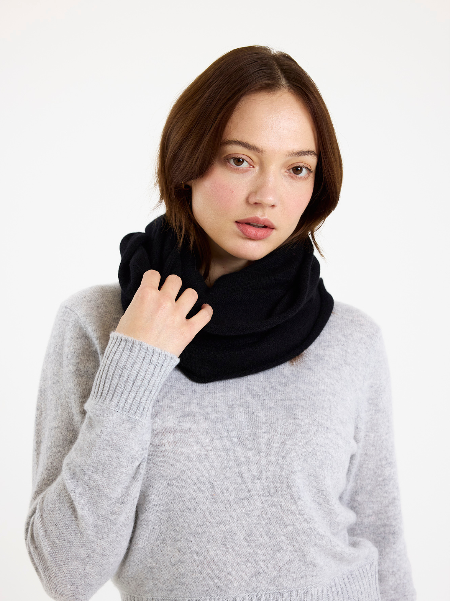 Woman wearing a black snood and grey sweater on a white background