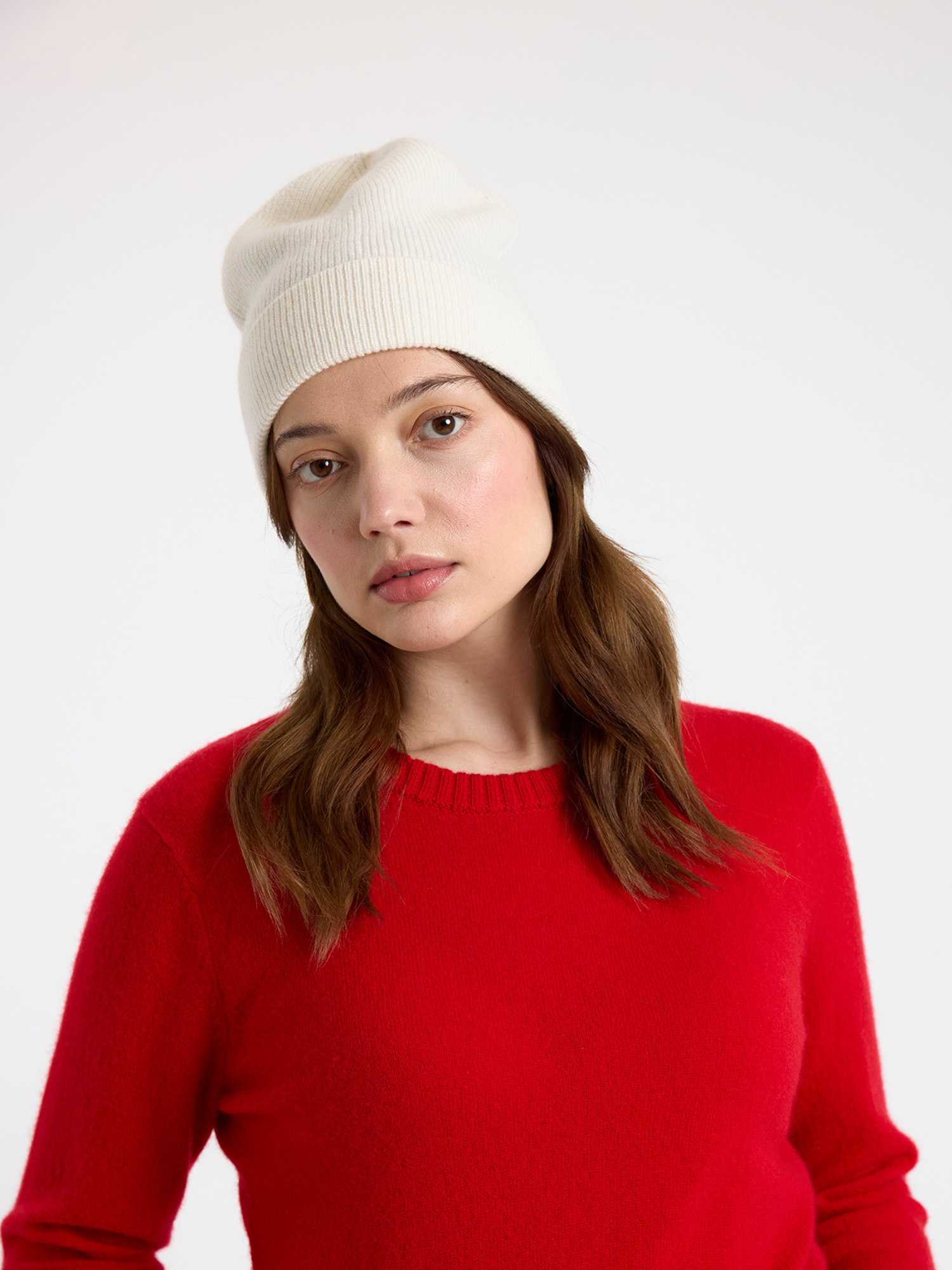 Woman wearing a white beanie and red sweater on a white background