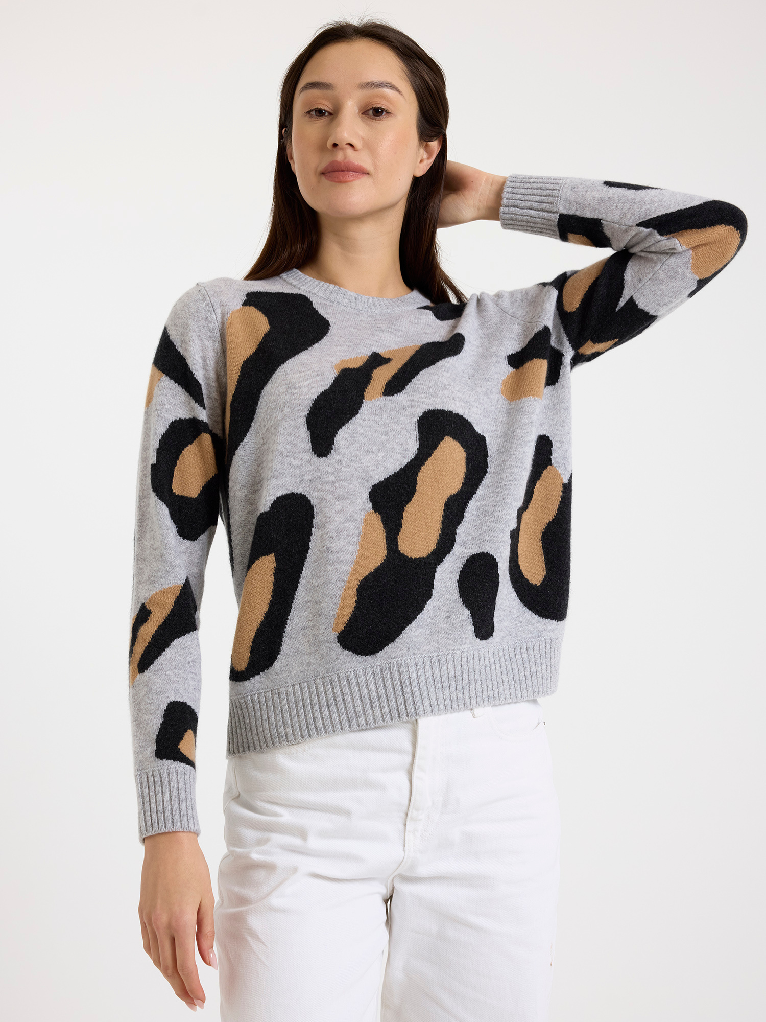 Woman wearing a grey sweater with leopard print patterns on a white background