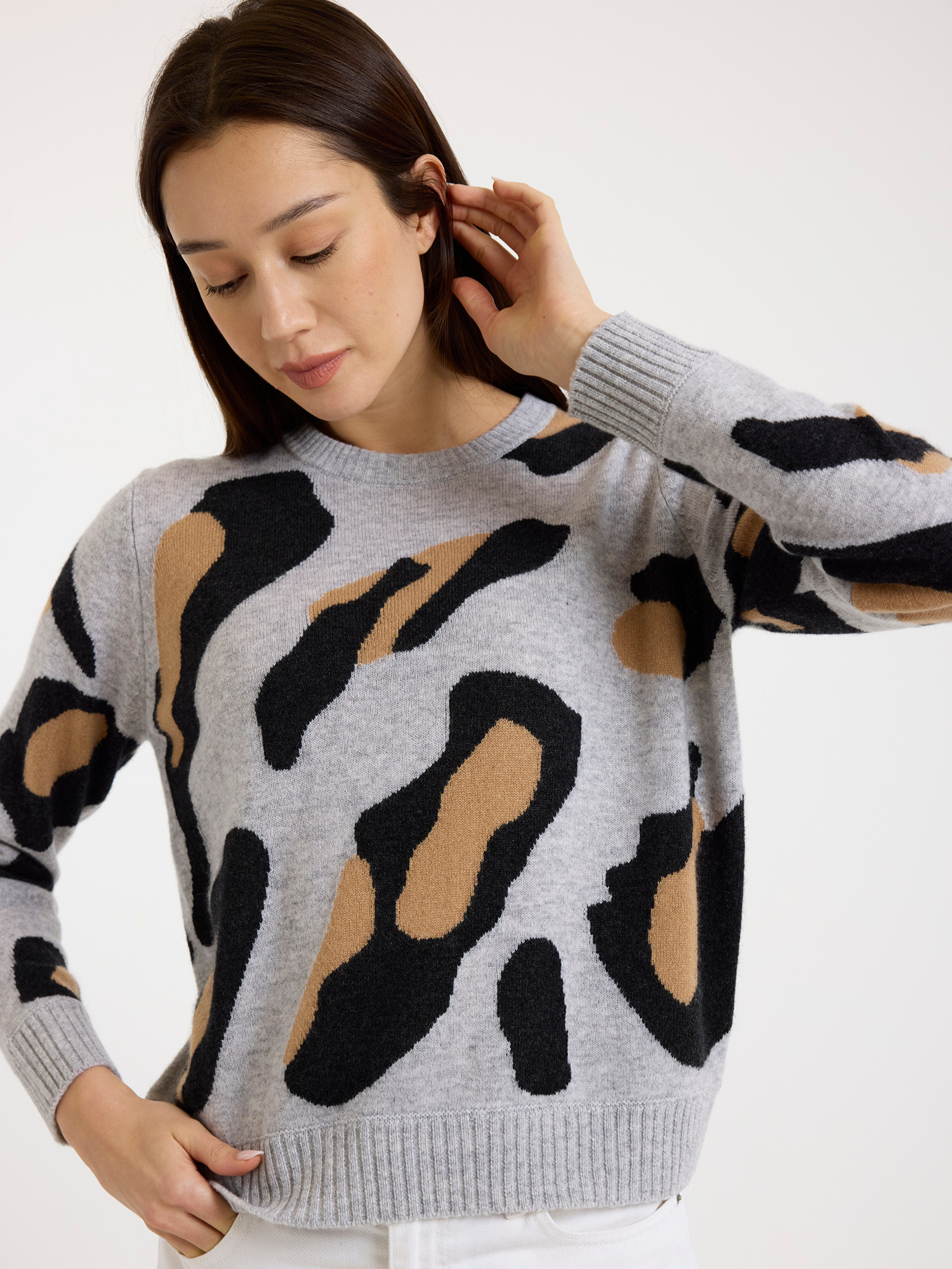 Woman wearing a grey sweater with a leopard print pattern on a white background