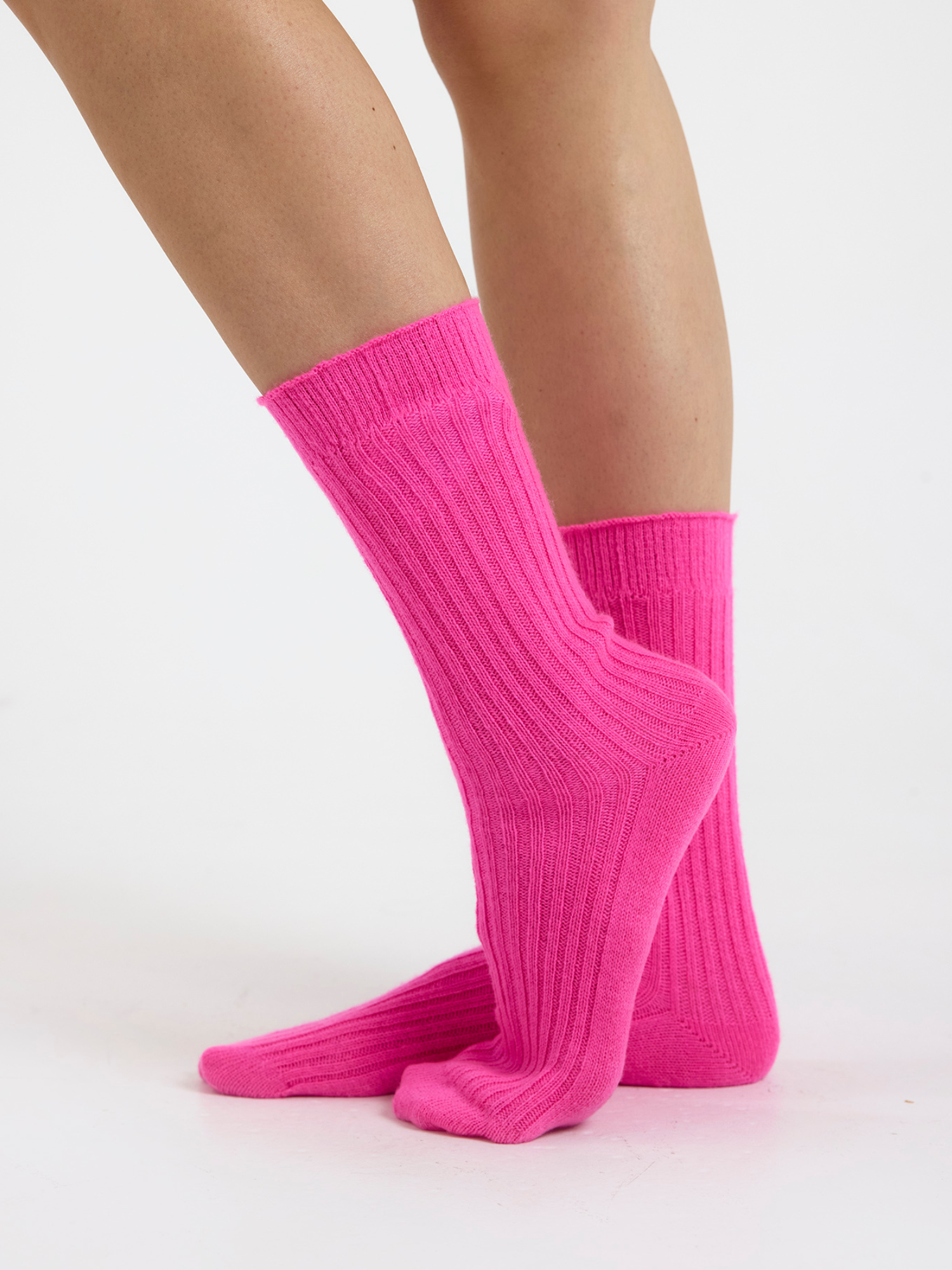 Person wearing bright pink socks on a white background