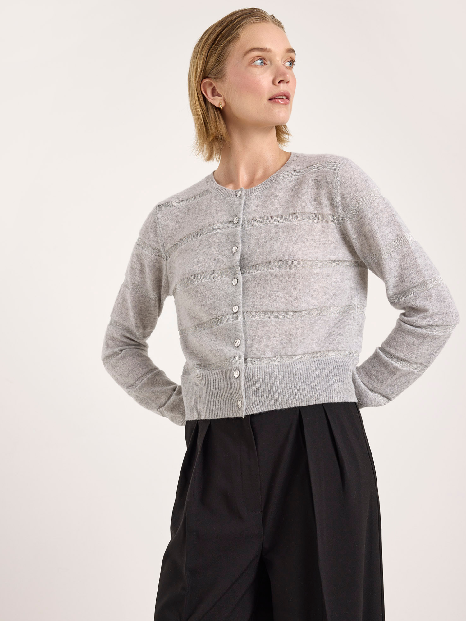 Woman wearing a gray cardigan and black pants on a white background