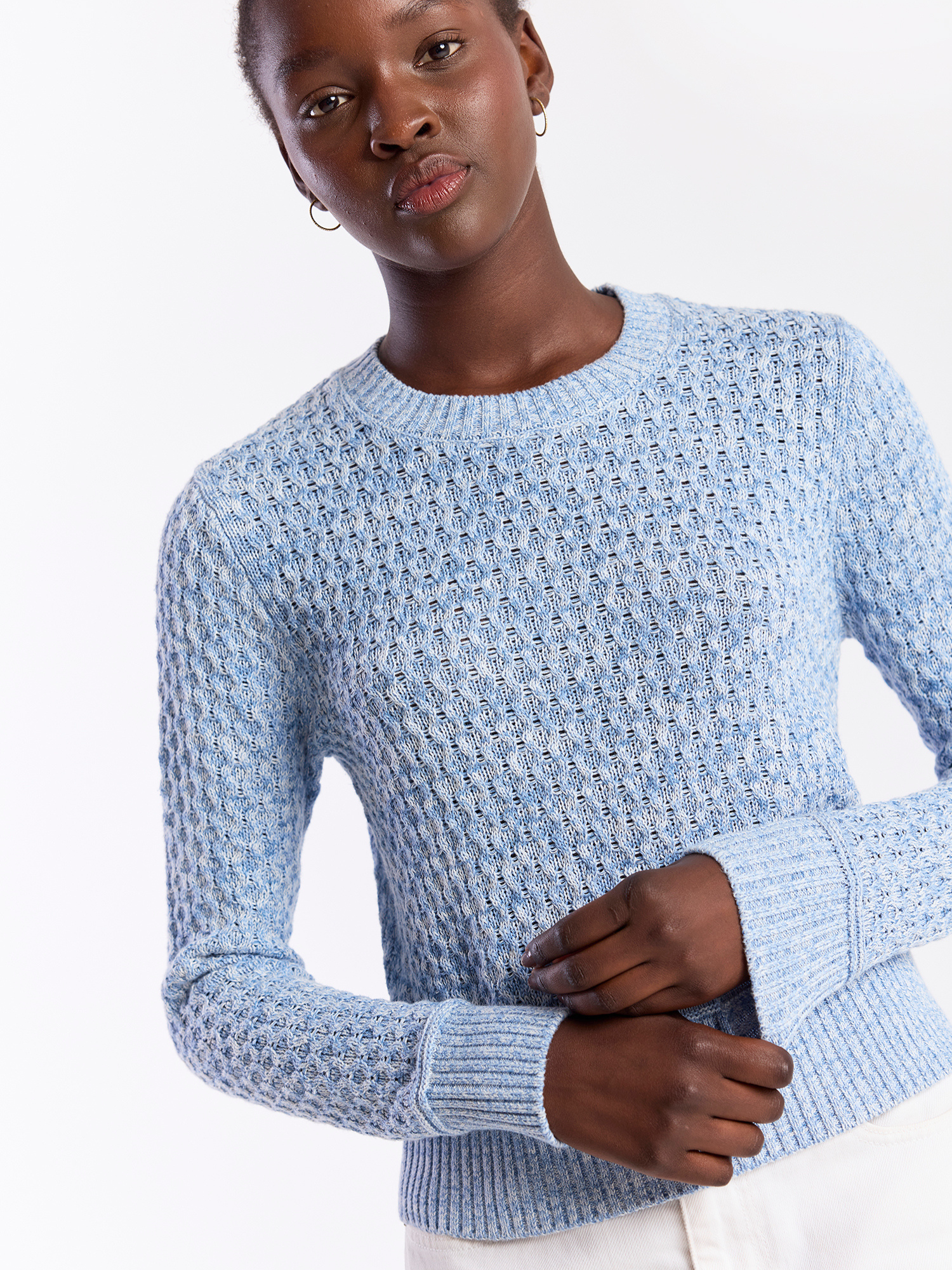 Person wearing a light blue textured sweater on a white background