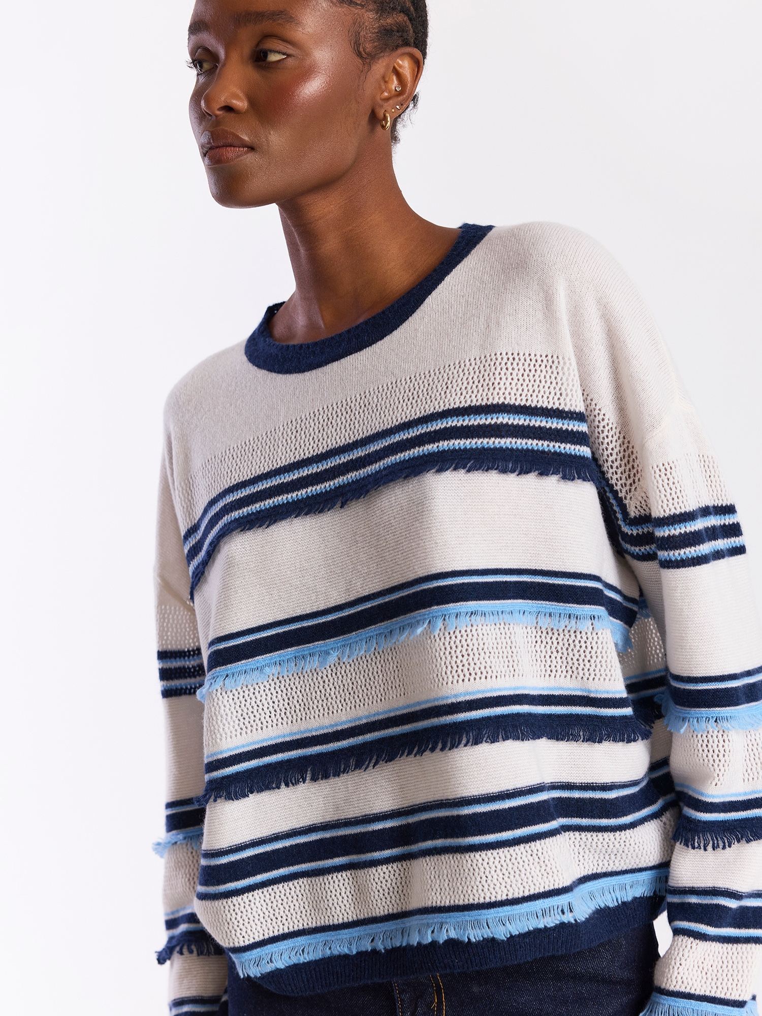 Woman wearing a striped sweater with blue and navy accents on a plain background