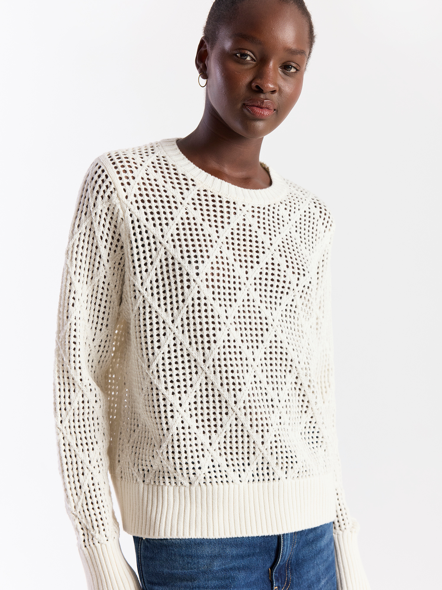 Woman wearing a white textured sweater against a plain background