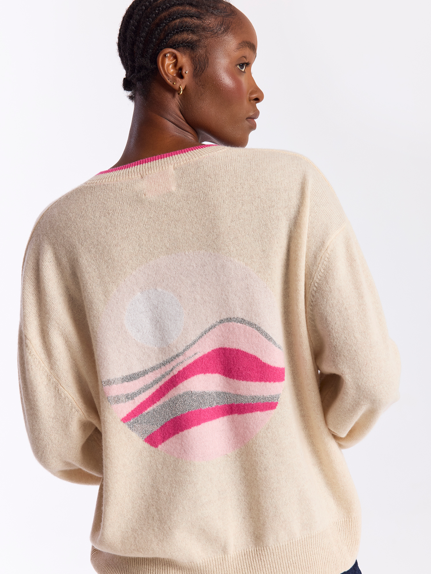 Person wearing a beige sweater with colorful design on a white background
