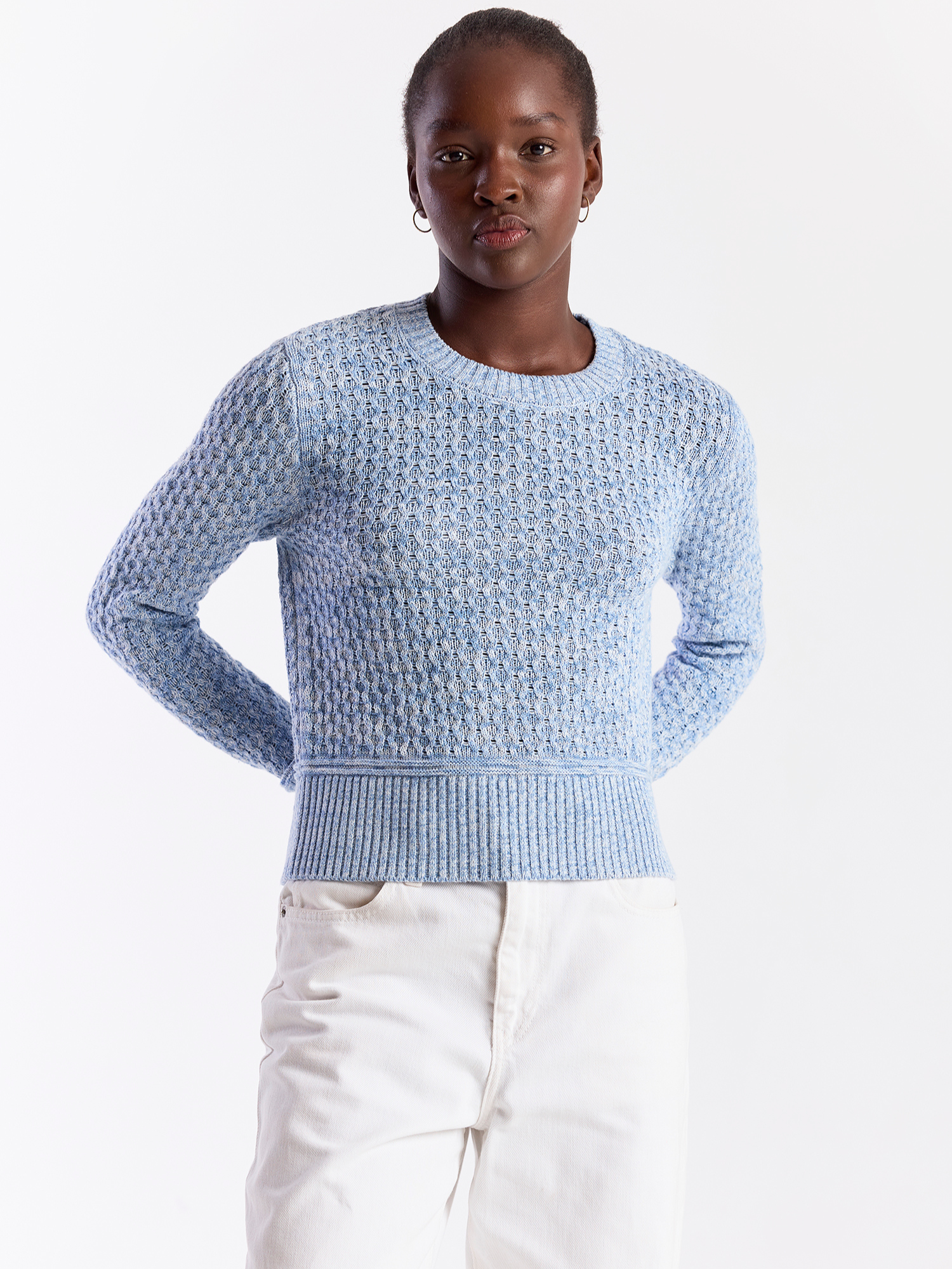 Person wearing a light blue textured sweater on a white background