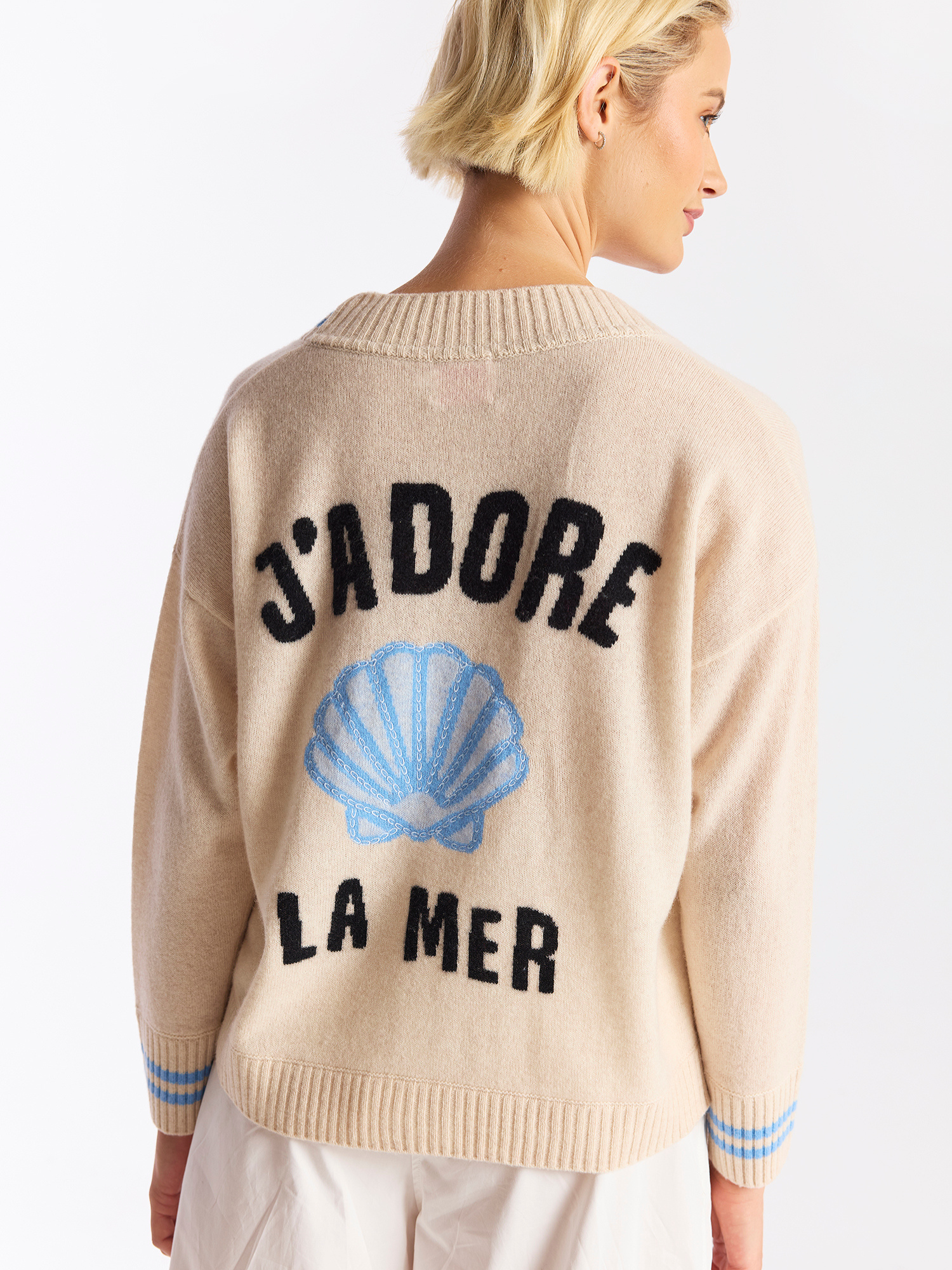 Beige sweater with 'J'adore La Mer' text and shell design on a white background