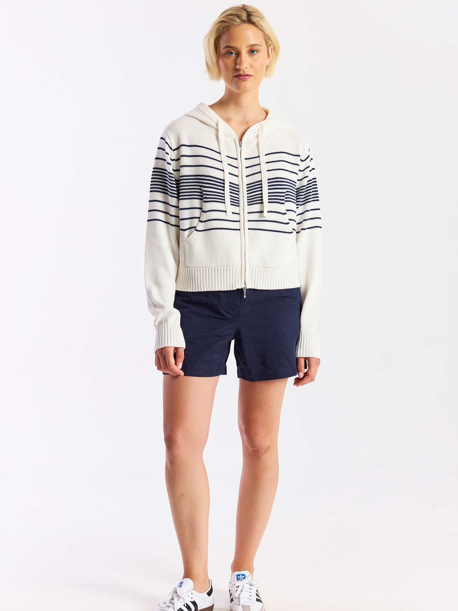 Person wearing a striped hoodie and navy shorts on a white background