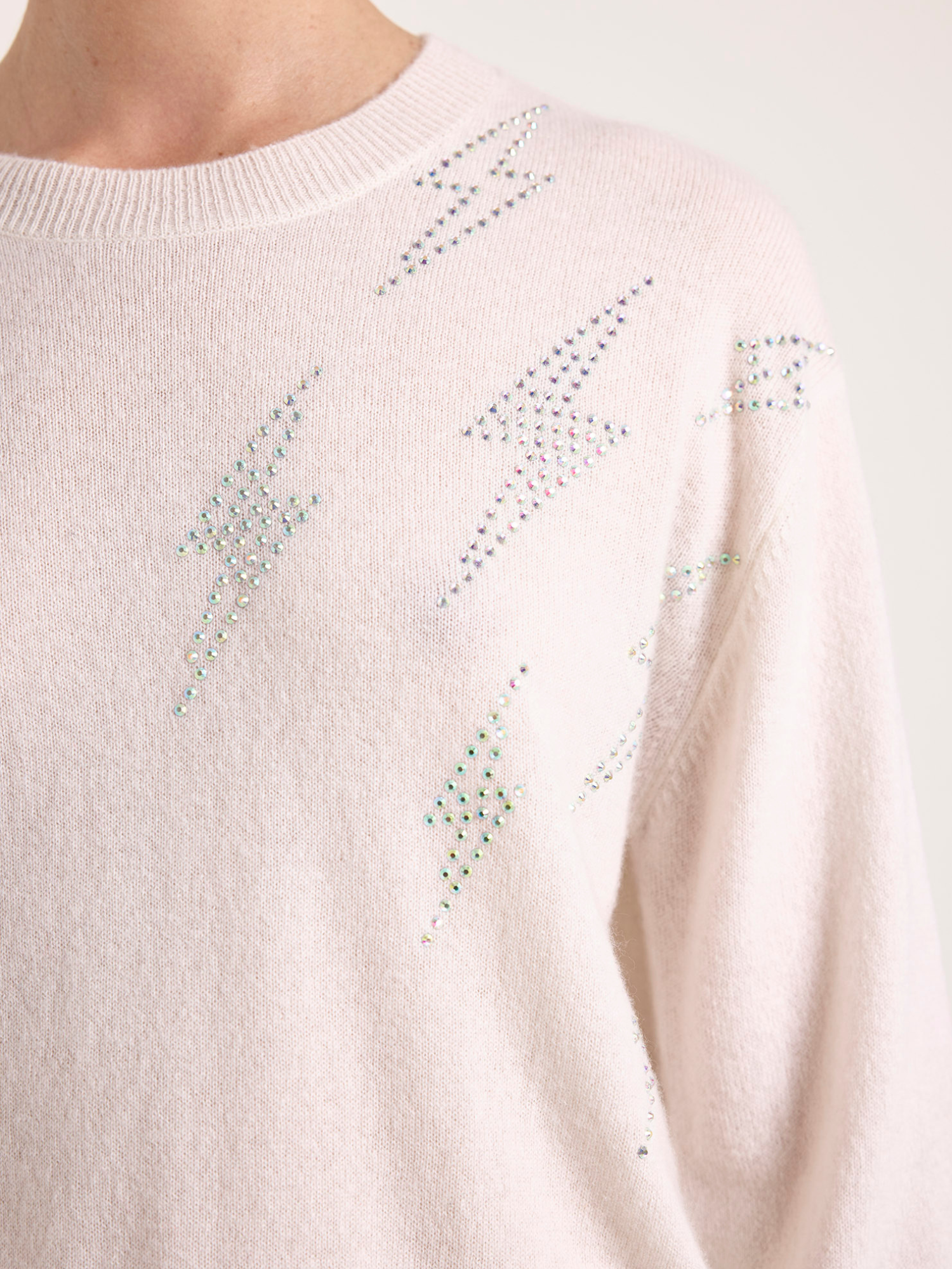 Close-up of a light pink sweater with decorative elements on a white background