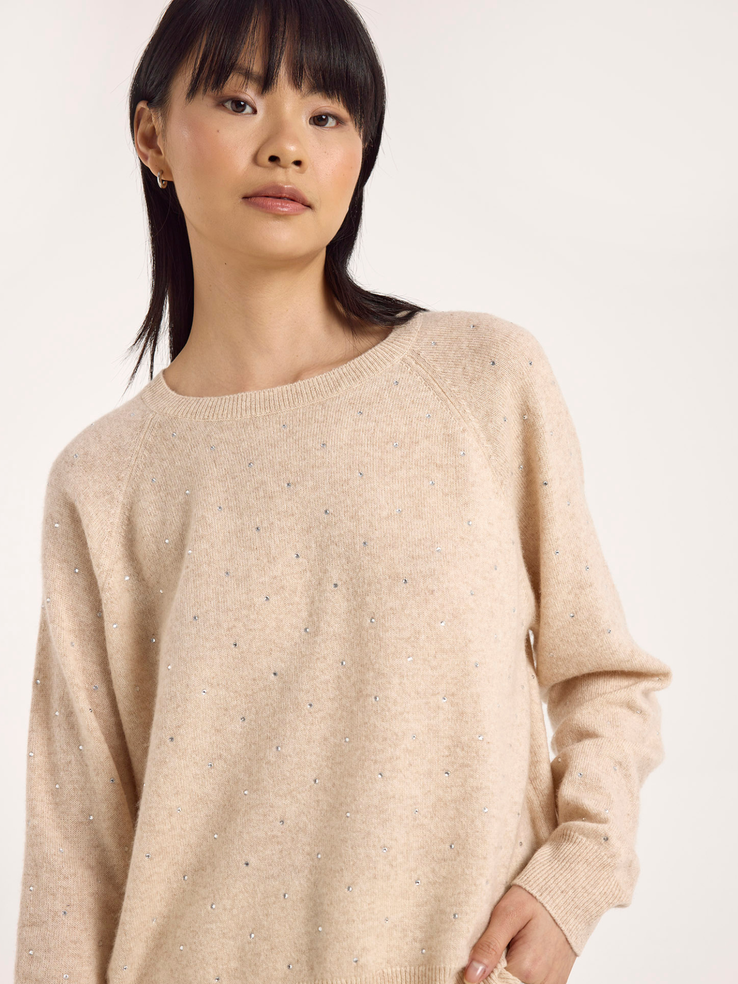 Woman wearing a beige sweater against a white background