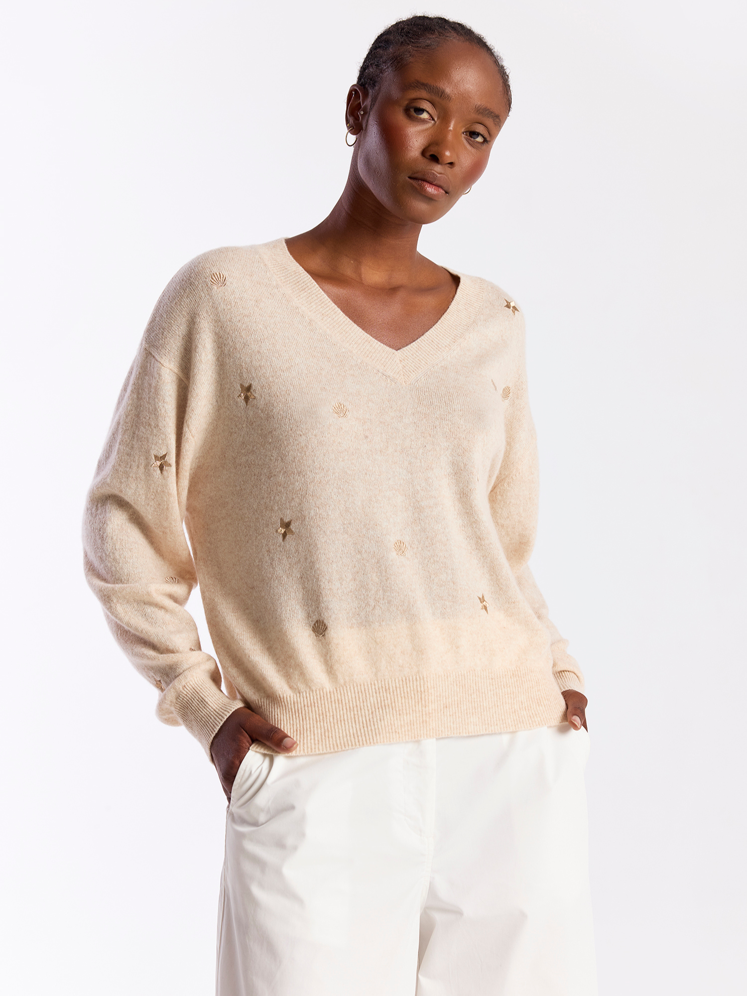 Woman wearing a beige sweater with star patterns on a white background