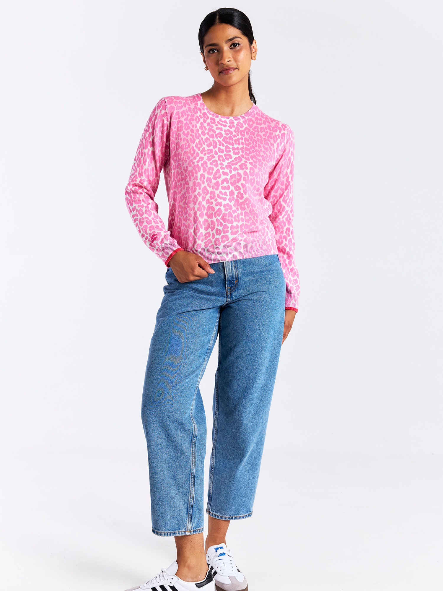 Woman wearing a pink leopard print top and blue jeans on a white background