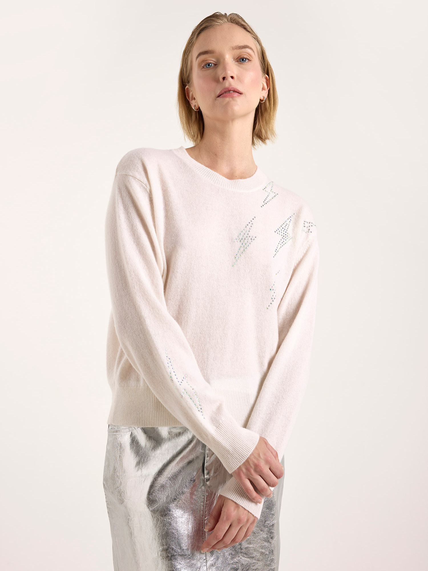 Woman wearing a light pink sweater with subtle patterns on a white background