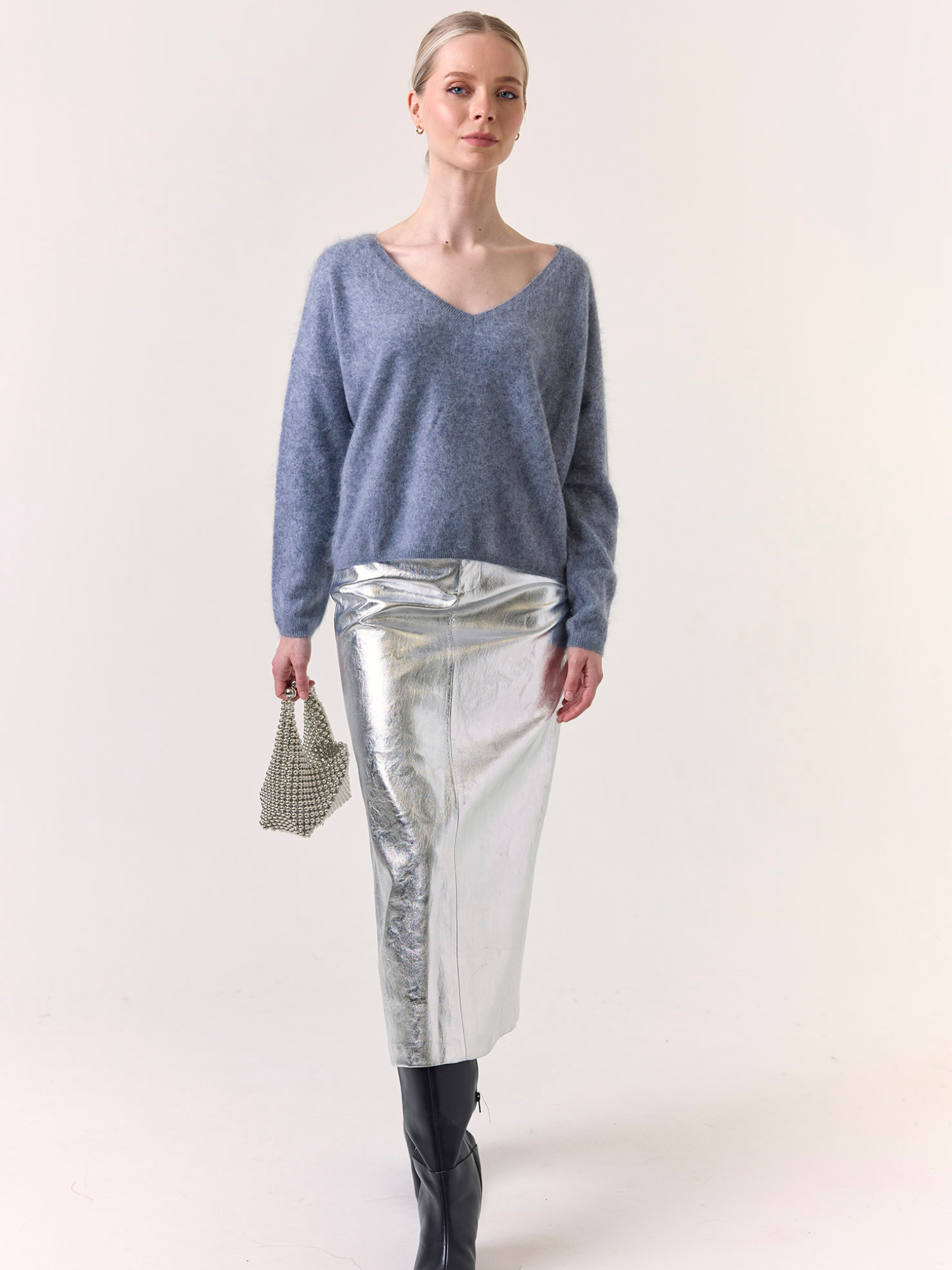 Woman wearing a blue sweater and silver skirt on a white background