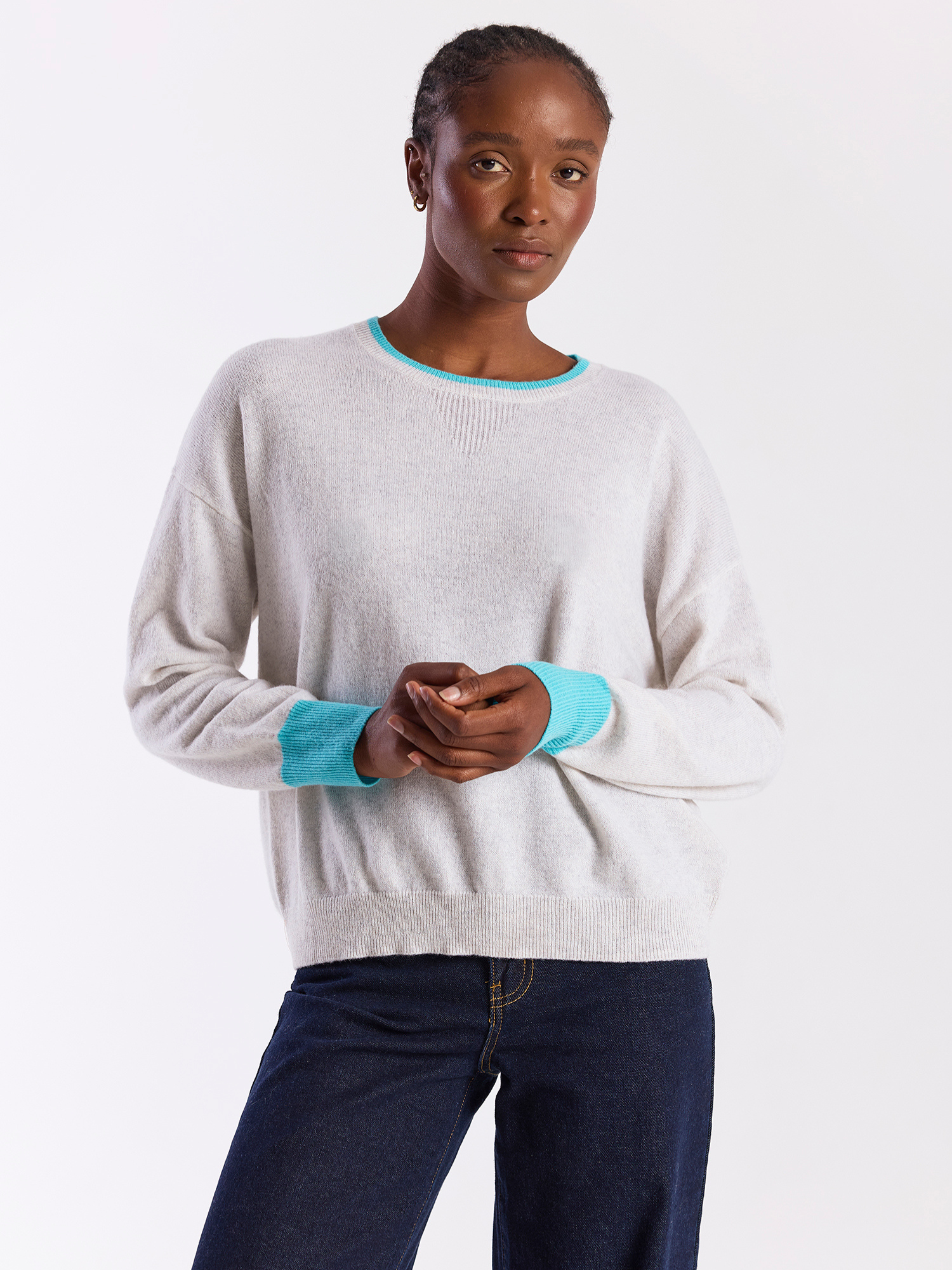 Woman wearing a light gray sweater with blue trim on a white background