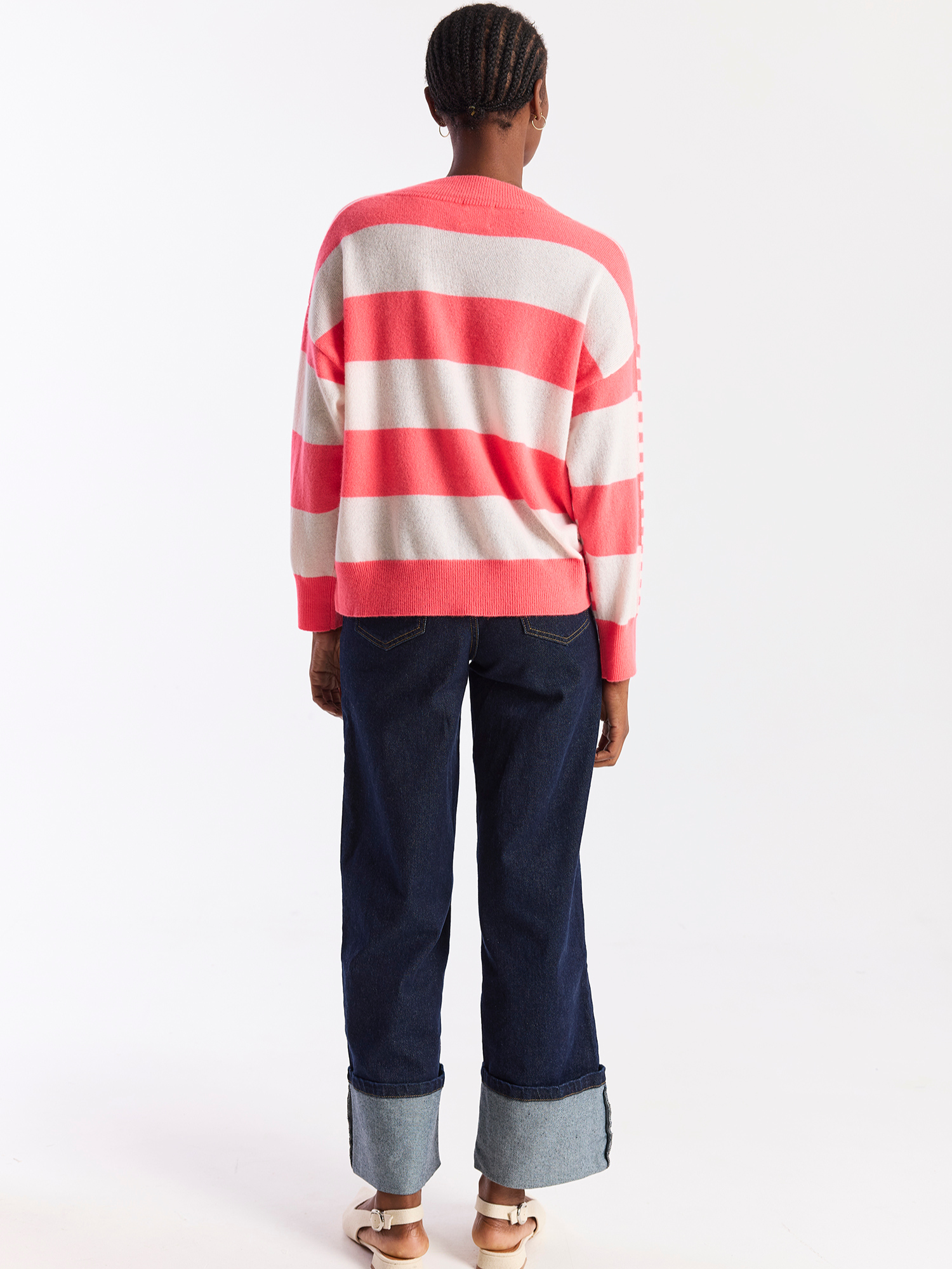 Person wearing a red and white striped sweater and dark blue jeans on a white background