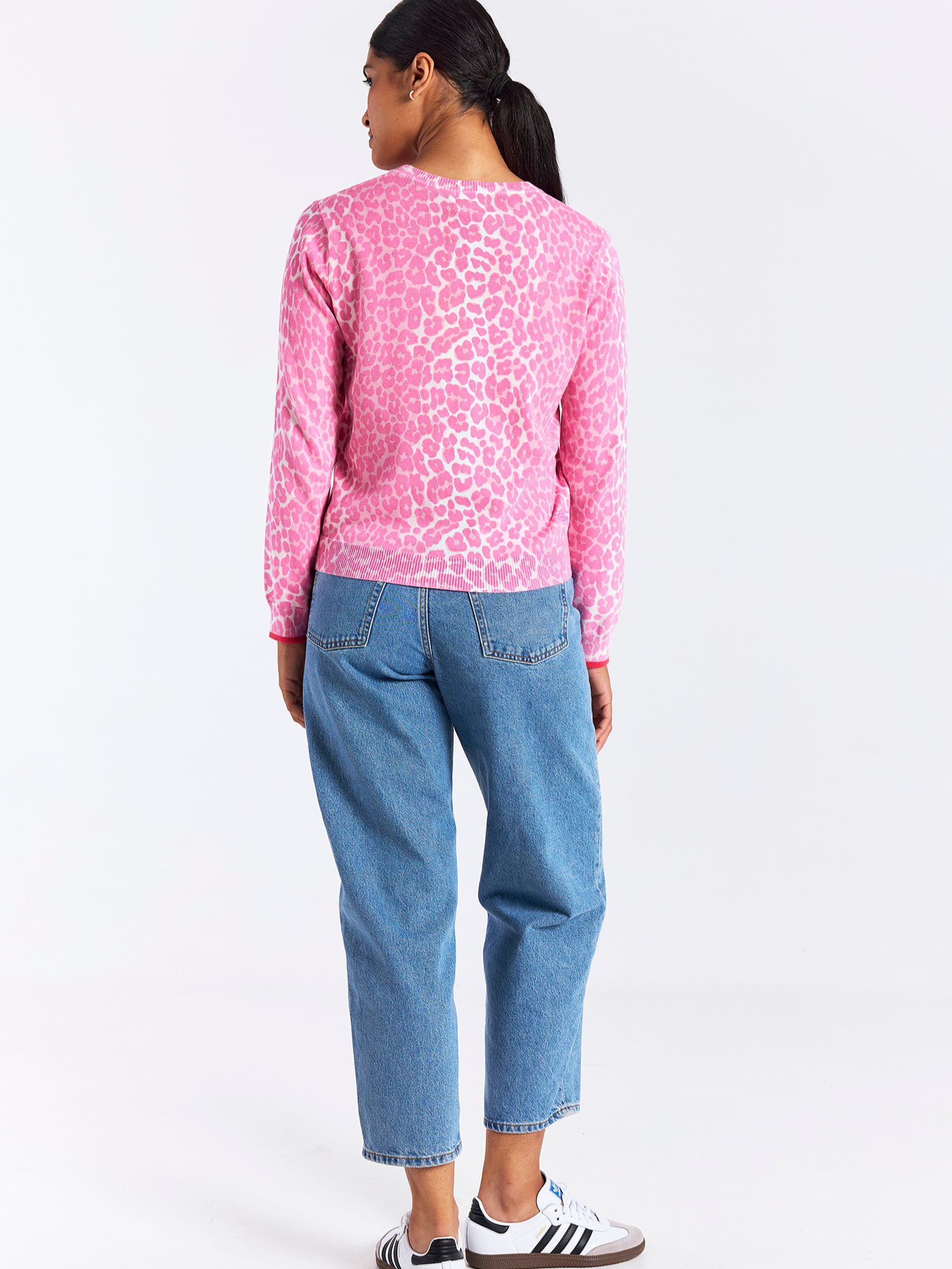 Person wearing a pink leopard print sweatshirt and blue jeans on a white background