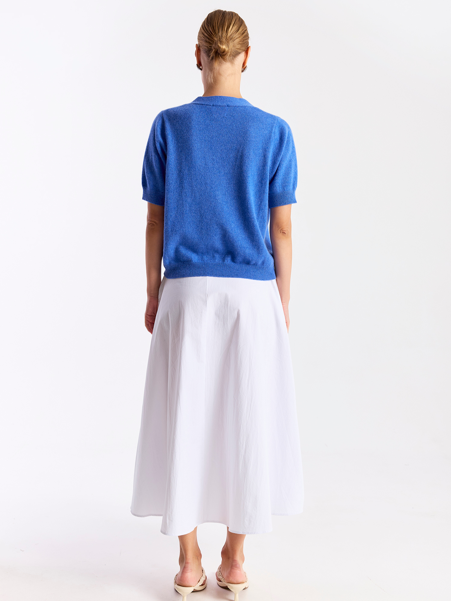 Person wearing a blue top and white skirt on a white background