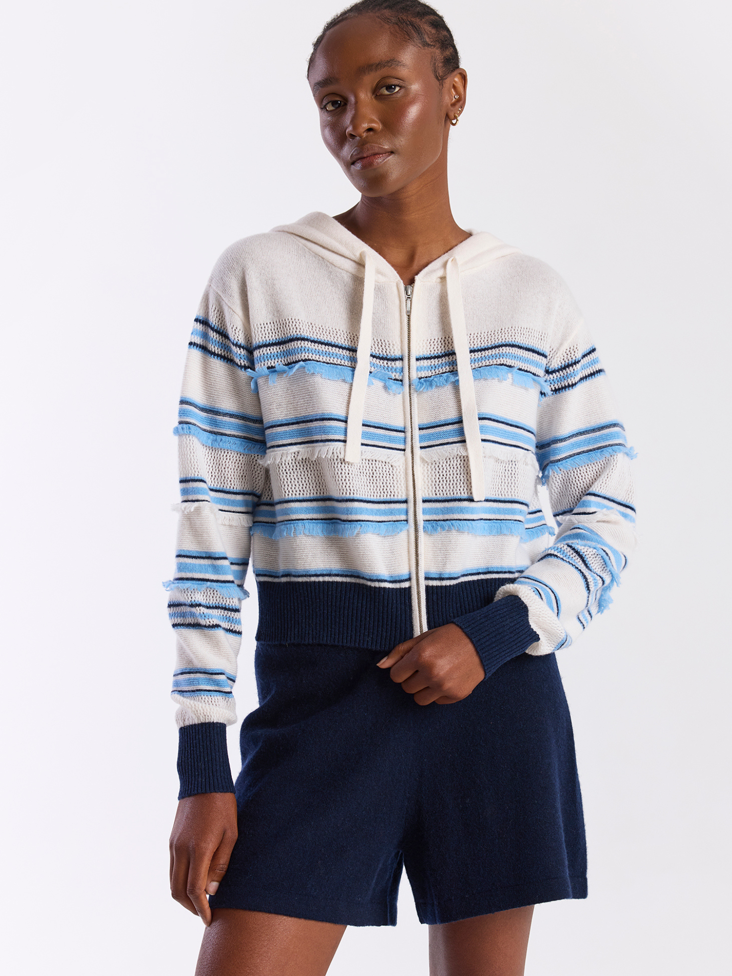 Person wearing a white and blue striped hoodie with navy shorts on a white background