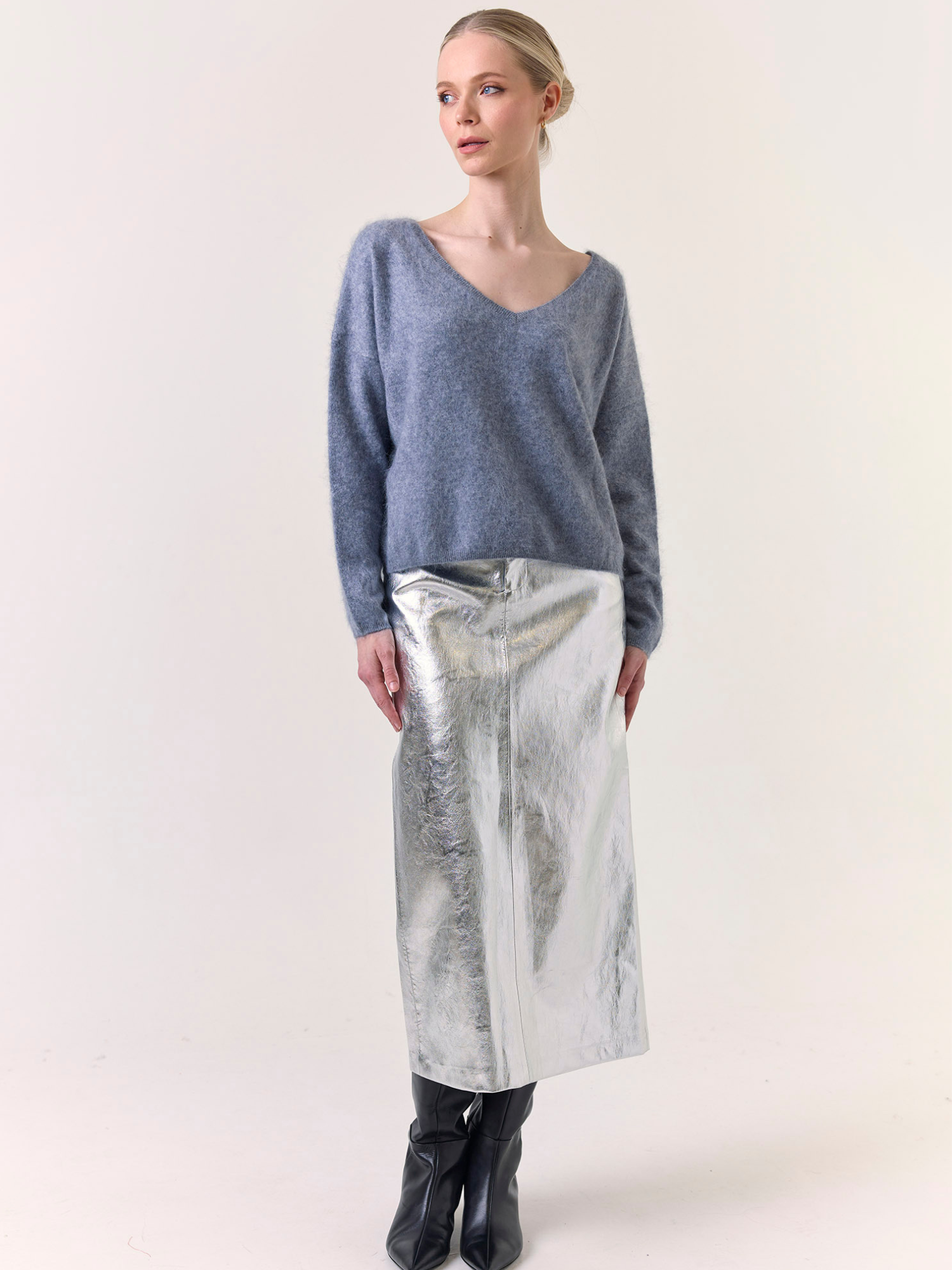 Woman wearing a blue sweater and silver skirt on a white background
